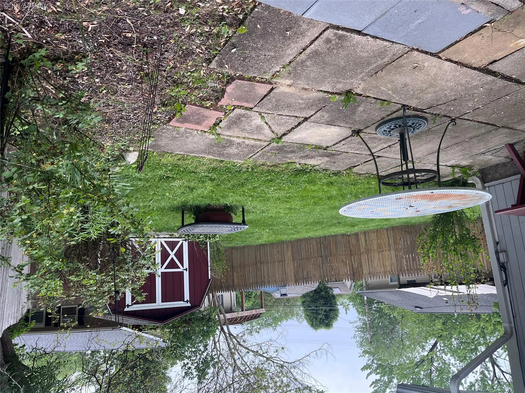 Expansive backyard with a square paver patio and a large grassy area Expansive backyard with a square paver patio and a large grassy area