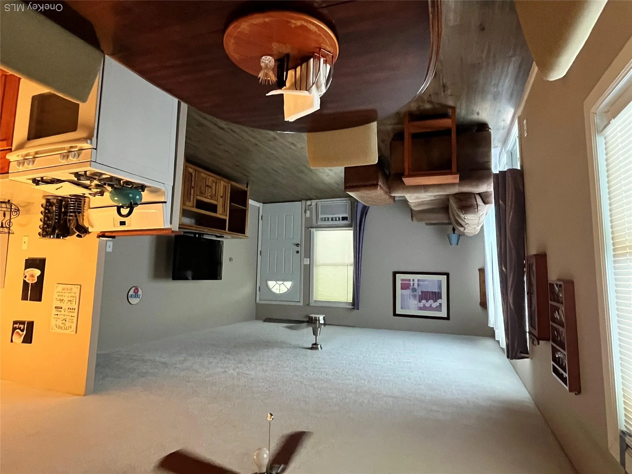 Open-concept living space featuring wood-finish flooring, a ceiling fan, and a white paneled entry door Open-concept living space featuring wood-finish flooring, a ceiling fan, and a white paneled entry door