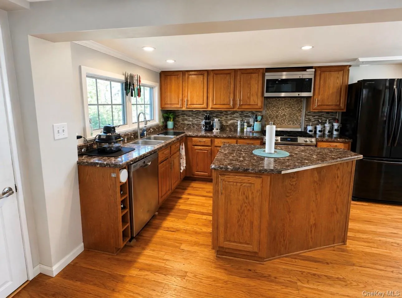 Kitchen featuring wood-finish cabinetry, patterned countertops, and a mosaic tile backsplash Kitchen featuring wood-finish cabinetry, patterned countertops, and a mosaic tile backsplash