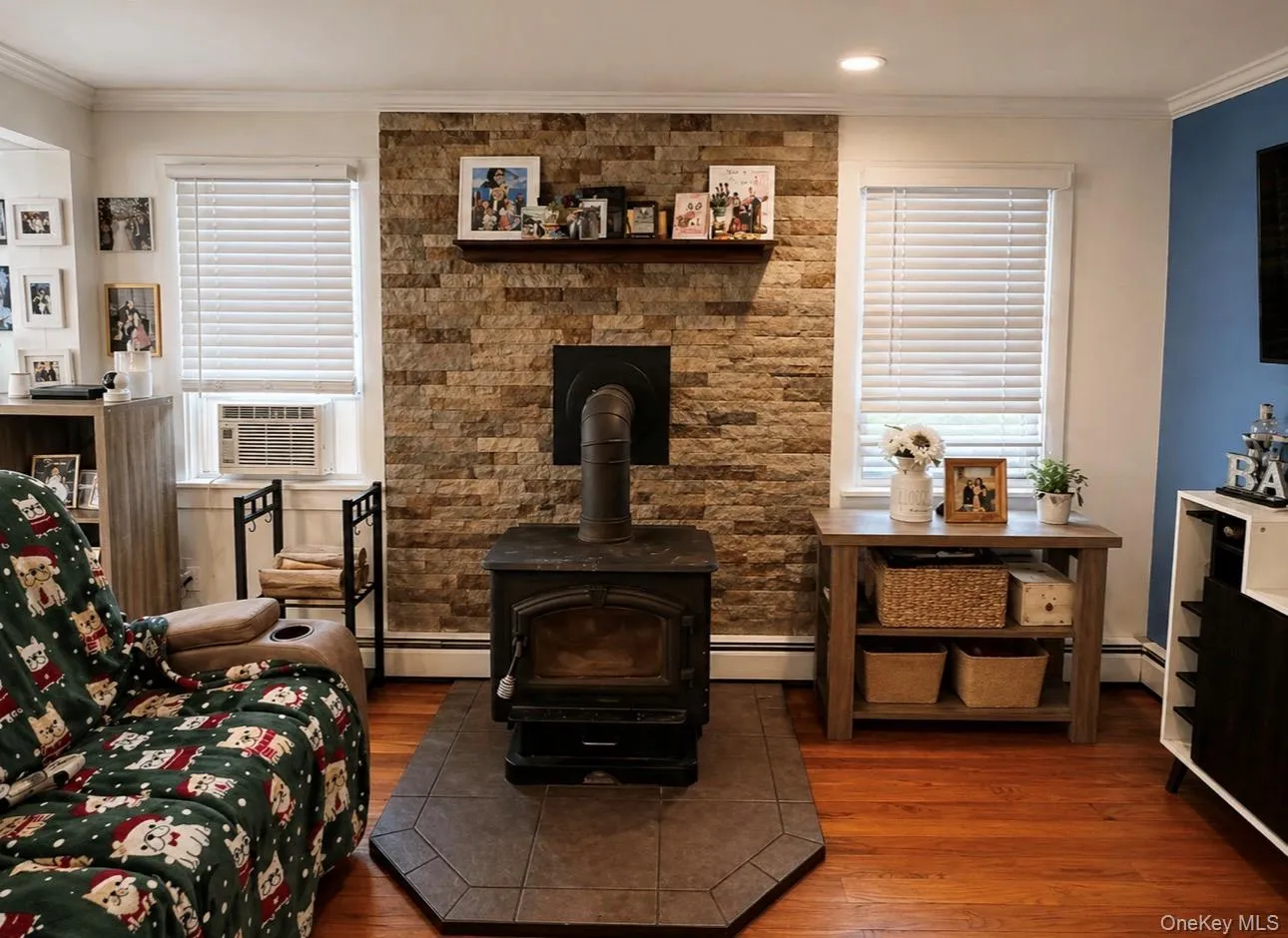 Living area featuring a stone accent wall with a wood-burning stove on a tiled hearth Living area featuring a stone accent wall with a wood-burning stove on a tiled hearth