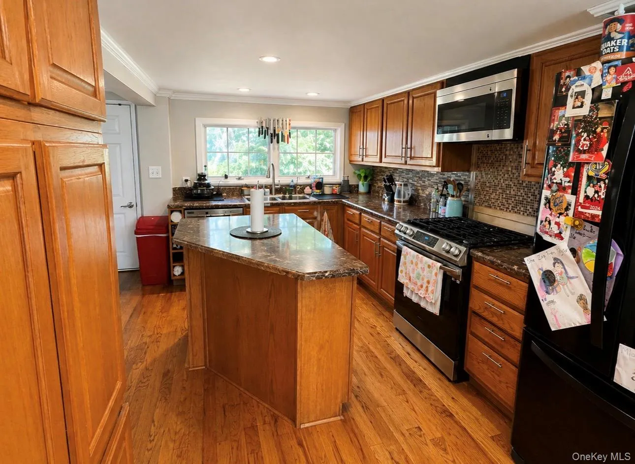 Kitchen featuring a central island with stone countertop, wood-finish flooring, and recessed lighting Kitchen featuring a central island with stone countertop, wood-finish flooring, and recessed lighting