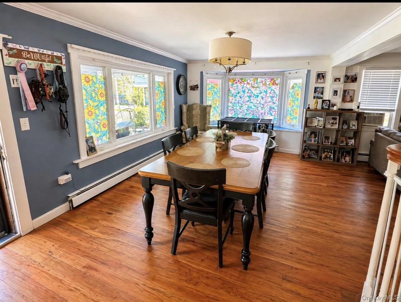 Spacious room featuring hardwood flooring, a multi-pane bay window, and a central ceiling light fixture Spacious room featuring hardwood flooring, a multi-pane bay window, and a central ceiling light fixture