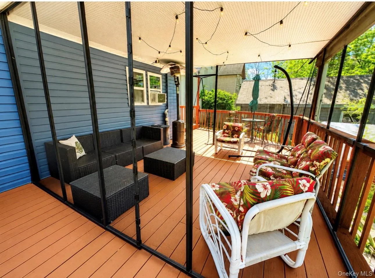 Expansive screened-in porch featuring wood-finish decking, a light-colored ceiling, and string lighting Expansive screened-in porch featuring wood-finish decking, a light-colored ceiling, and string lighting