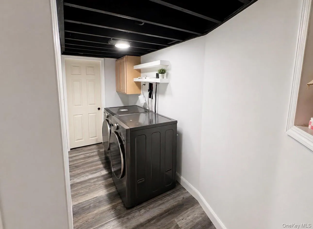 Dedicated laundry area featuring wood-finish flooring and a white paneled door Dedicated laundry area featuring wood-finish flooring and a white paneled door