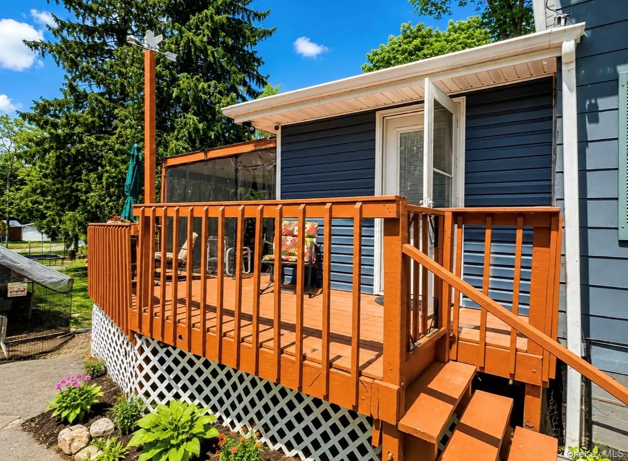 Expansive wood deck with stairs and lattice skirting, featuring a screened porch entry Expansive wood deck with stairs and lattice skirting, featuring a screened porch entry