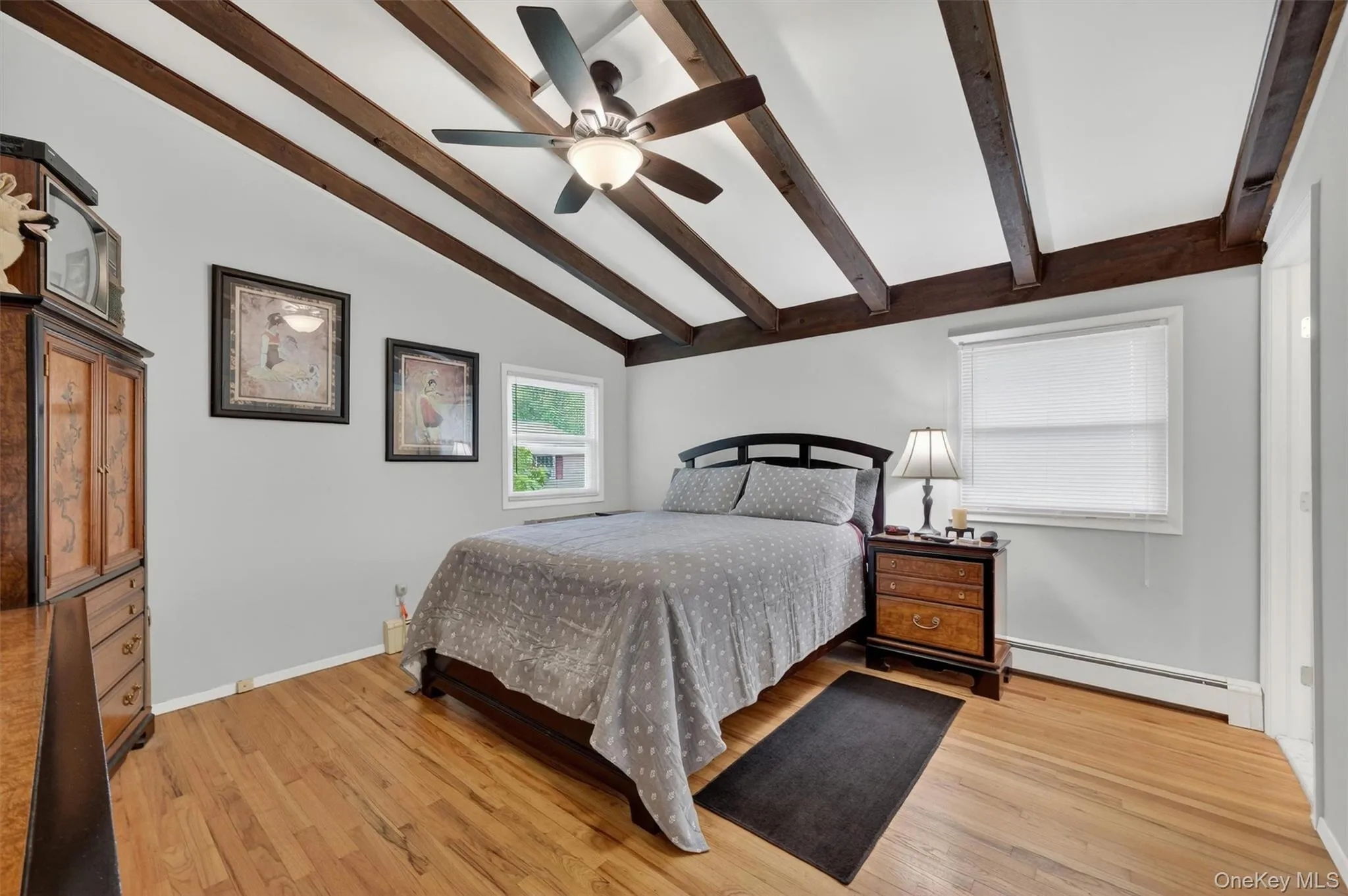 Primary bedroom with beamed ceilings, ceiling fan and hardwood floors Primary bedroom with beamed ceilings, ceiling fan and hardwood floors