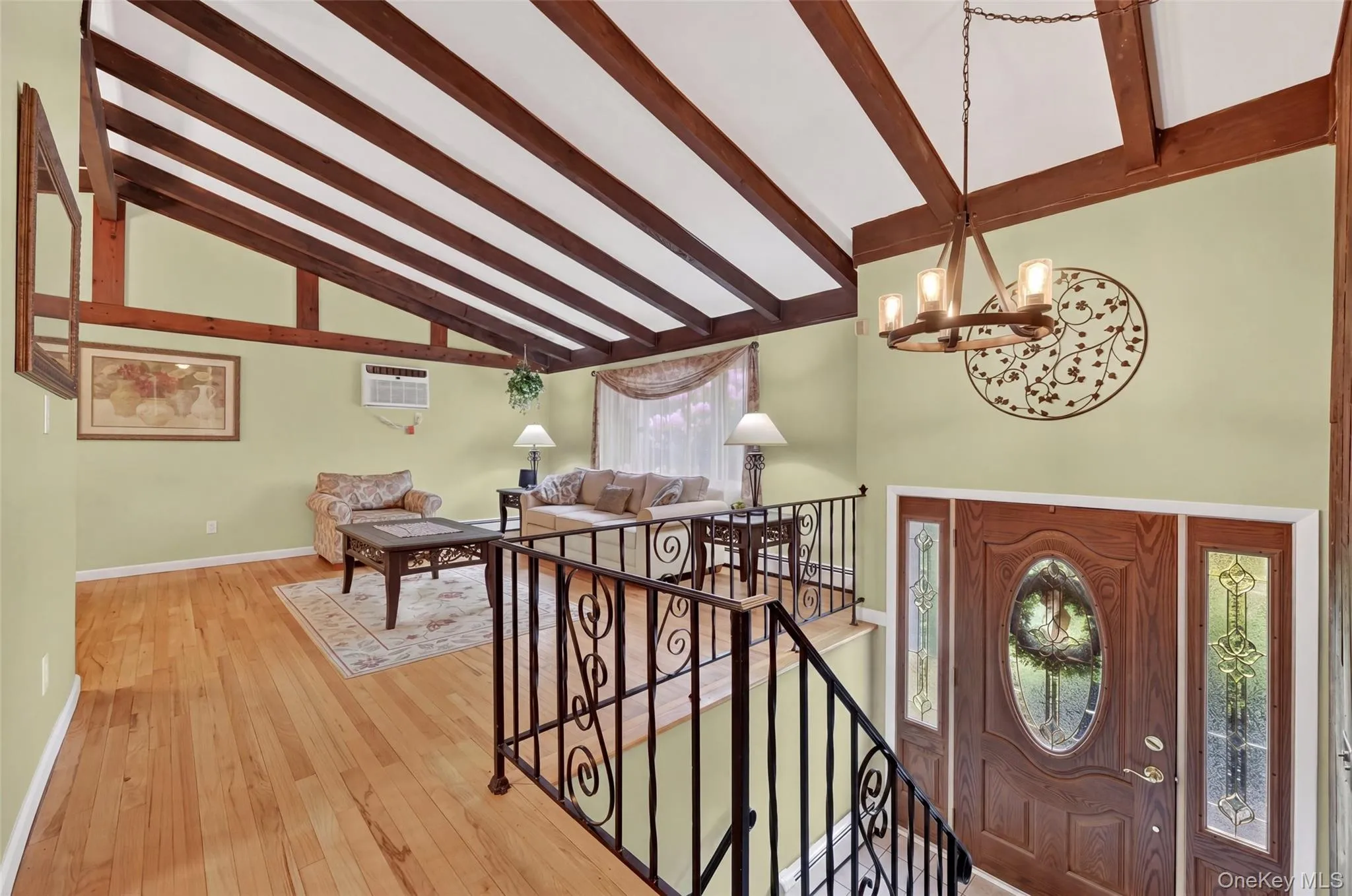 Living room with Vaulted ceiling with exposed wood beams, hardwood flooring, tiled entry foyer with newer front door Living room with Vaulted ceiling with exposed wood beams, hardwood flooring, tiled entry foyer with newer front door