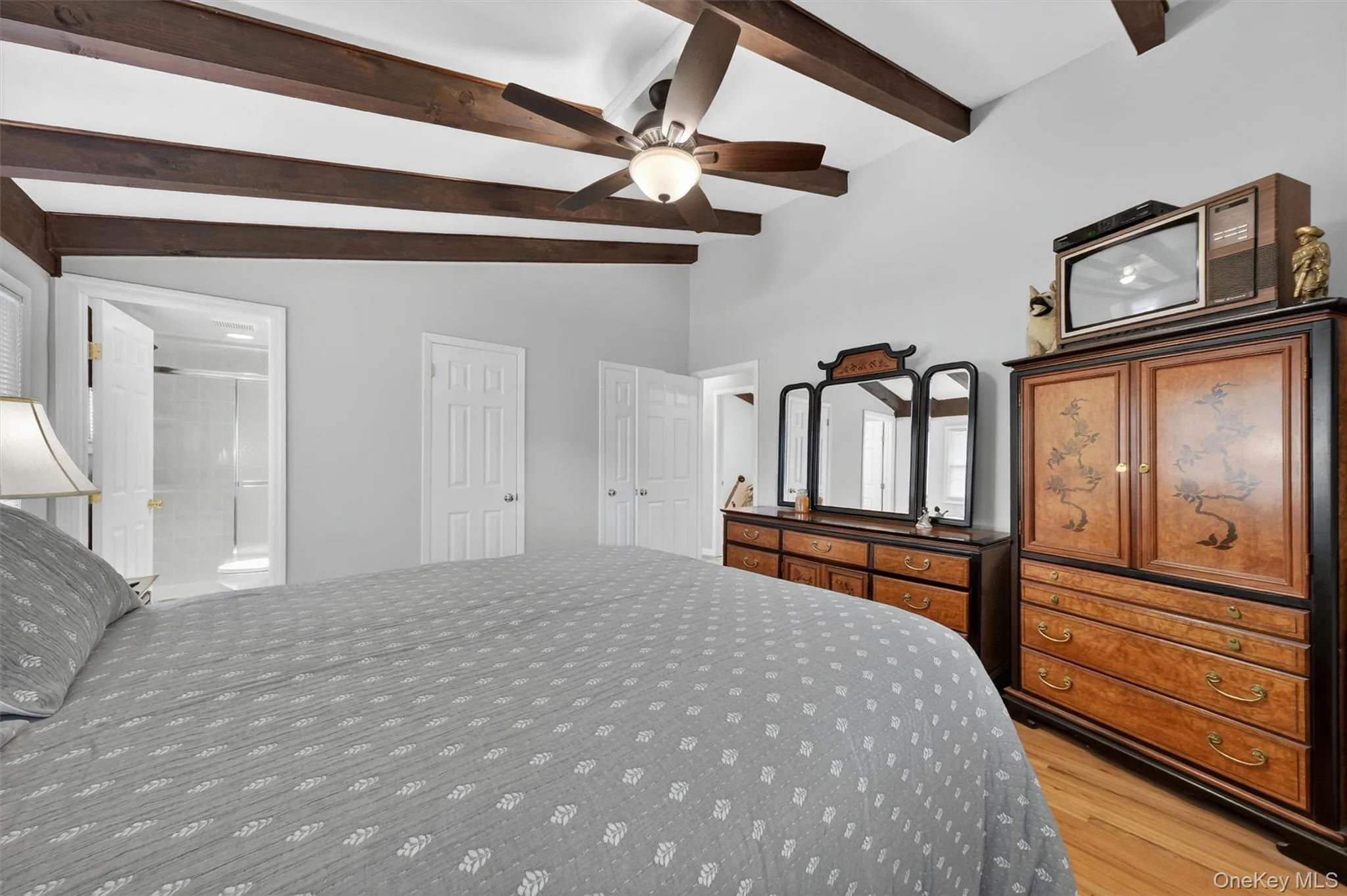 Primary bedroom with beamed ceilings, ceiling fan and hardwood floors Primary bedroom with beamed ceilings, ceiling fan and hardwood floors
