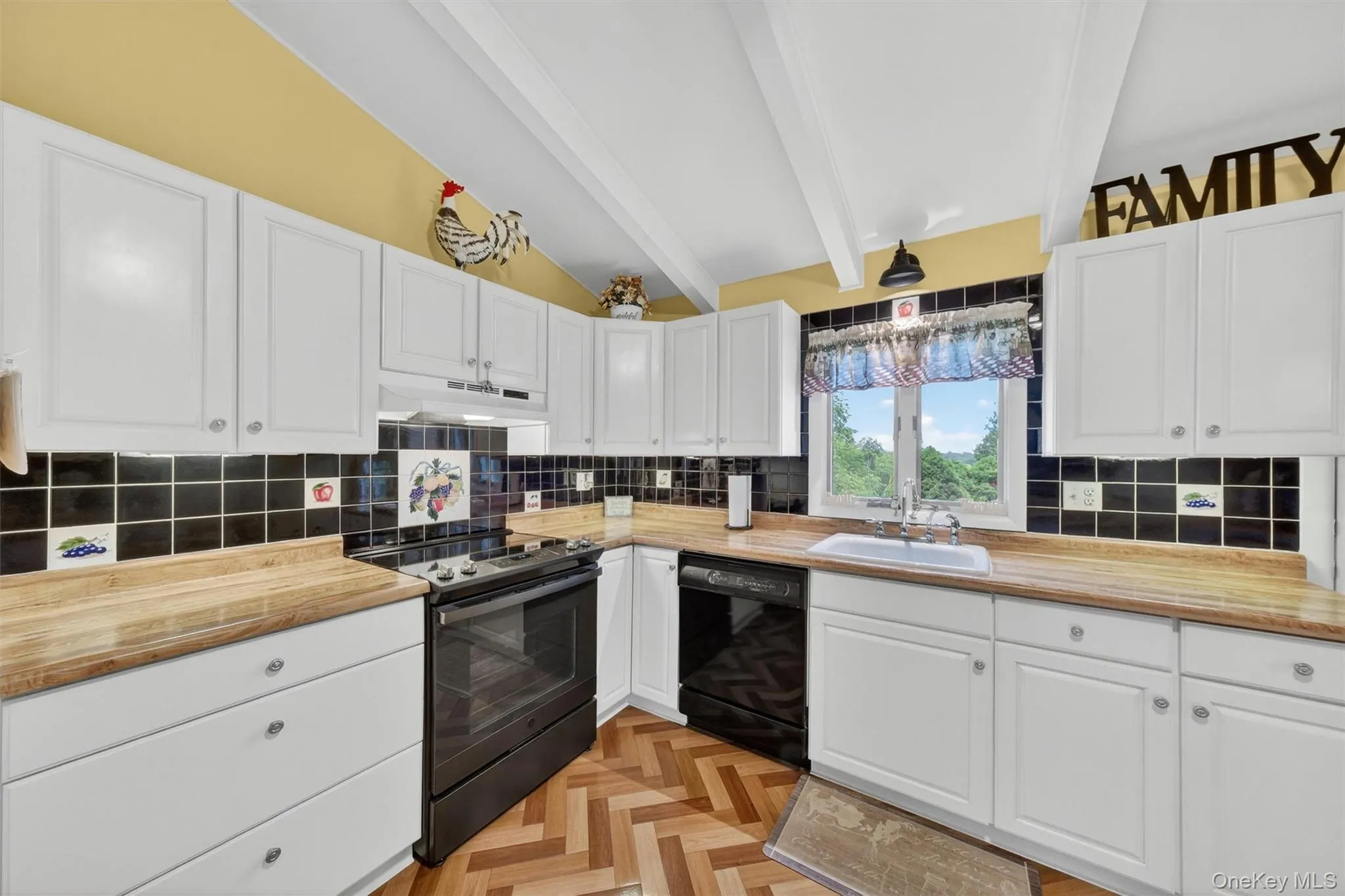 Kitchen featuring vaulted ceilings with exposed beams, wood-finish flooring in a herringbone pattern, white cabinetry, breakfast bar, tile backsplash, cabinet lighting and light wood-finish countertops Kitchen featuring vaulted ceilings with exposed beams, wood-finish flooring in a herringbone pattern, white cabinetry, breakfast bar, tile backsplash, cabinet lighting and light wood-finish countertops