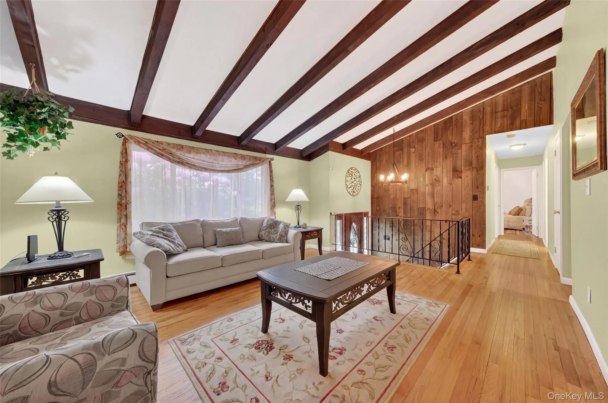 Living room with Vaulted ceiling with exposed wood beams, hardwood flooring, wood panel accent wal Living room with Vaulted ceiling with exposed wood beams, hardwood flooring, wood panel accent wal