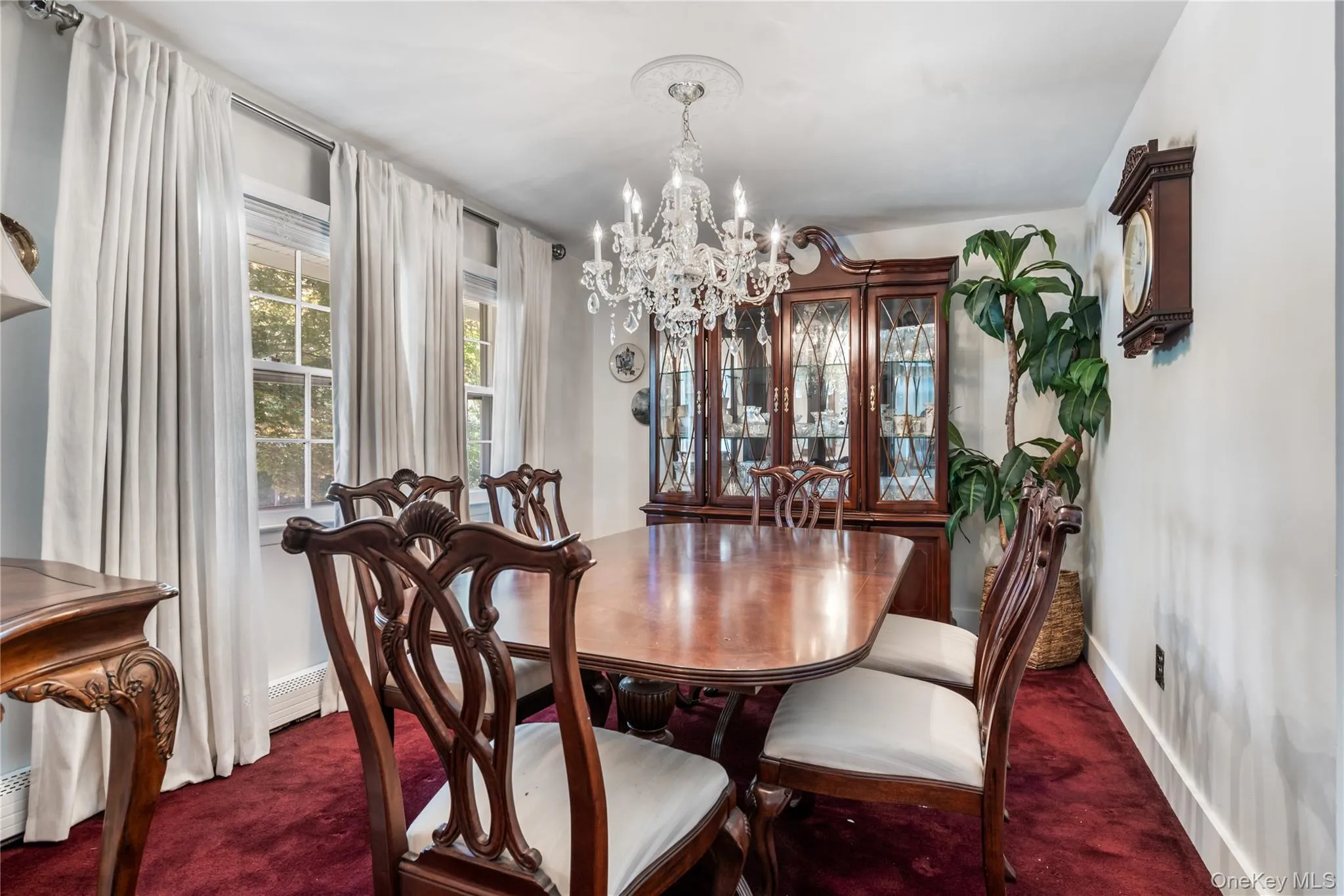 Formal dining area featuring a crystal chandelier and plush red carpeting Formal dining area featuring a crystal chandelier and plush red carpeting