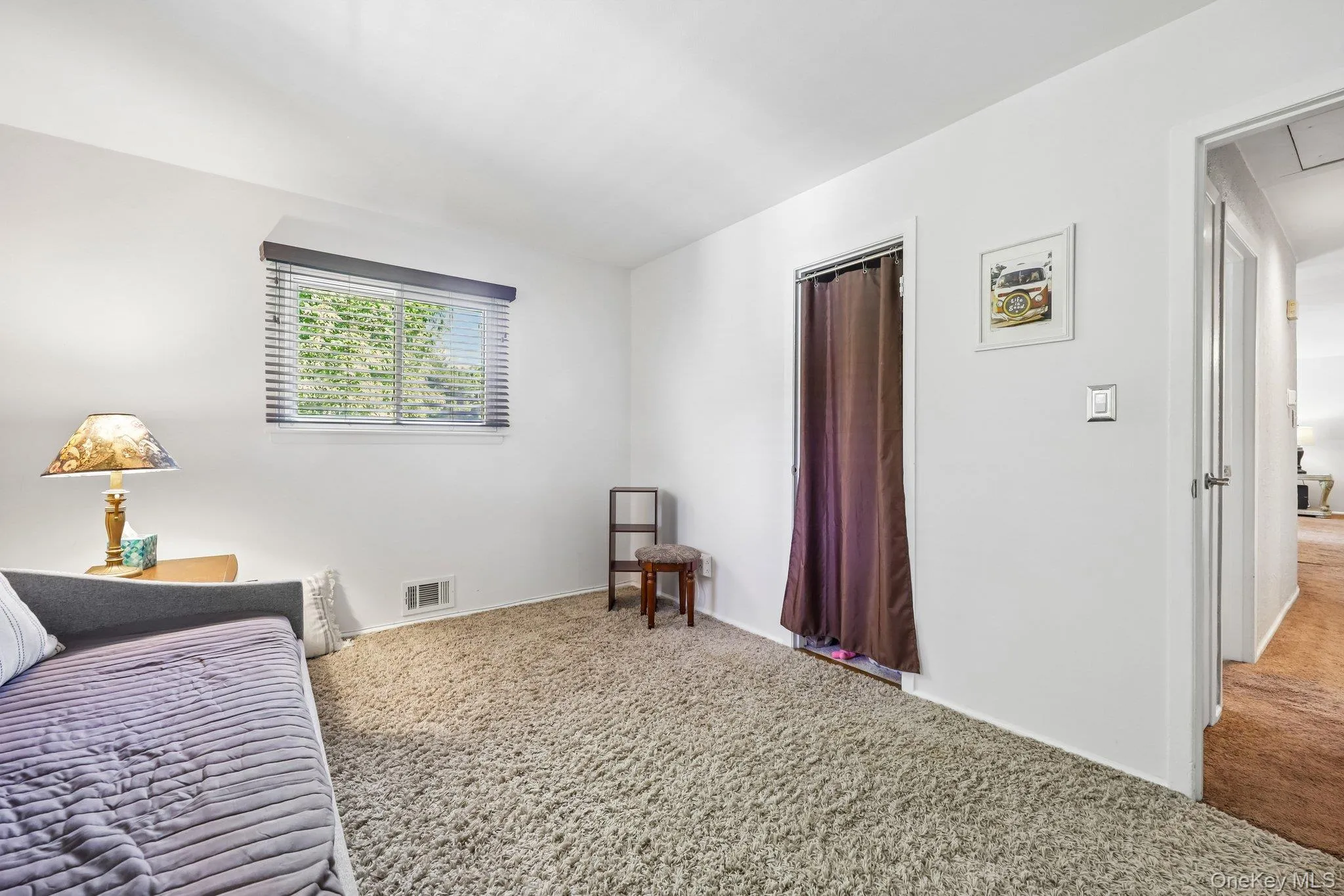 Bright white bedroom with wood paneled wall, carpet over wood floor, closet, white moulding, and two windows bringing in plenty of light from front and side of home. Bright white bedroom with wood paneled wall, carpet over wood floor, closet, white moulding, and two windows bringing in plenty of light from front and side of home.