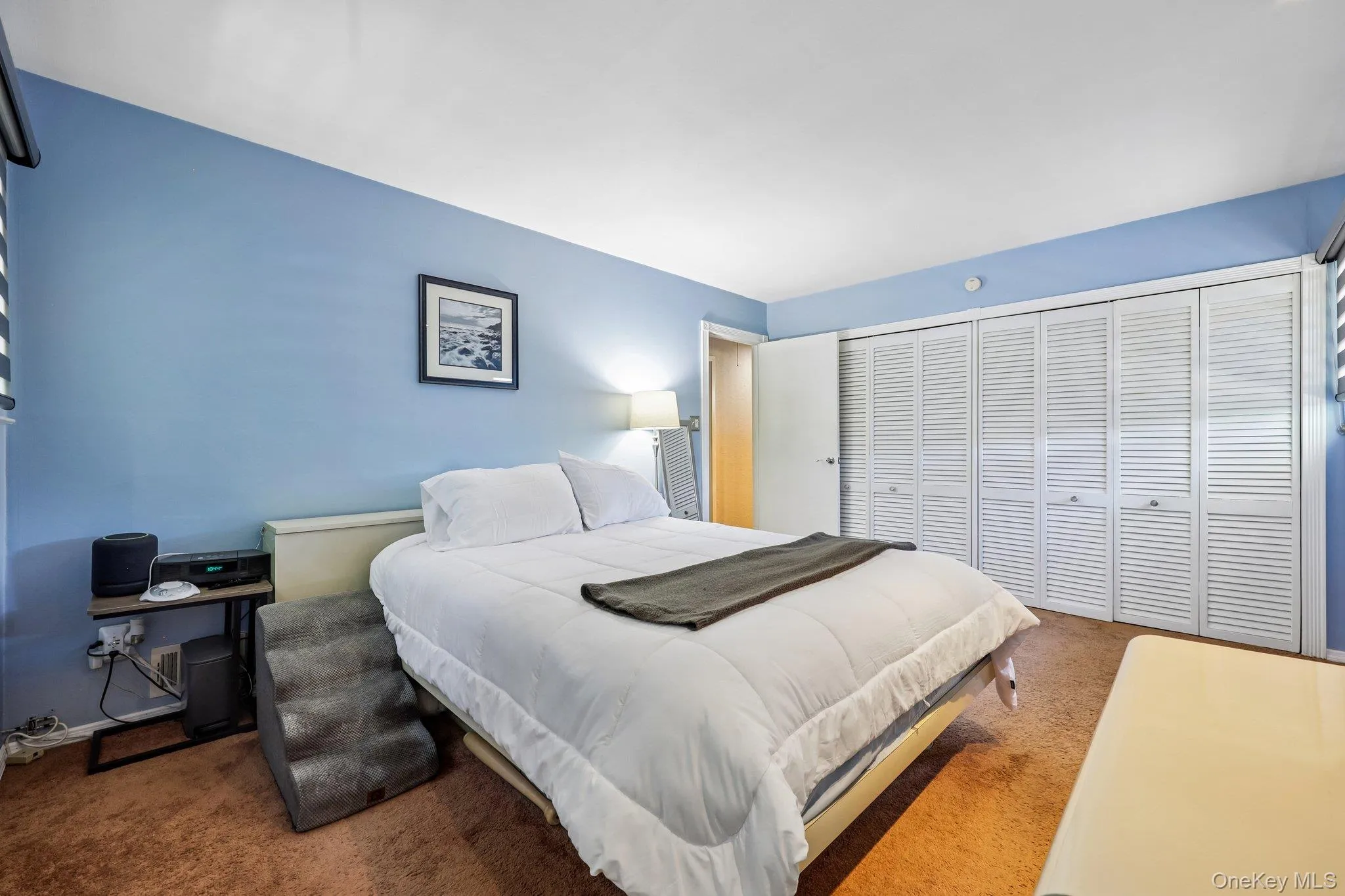Large Primary Bedroom featuring light blue walls, carpet over wood flooring, two windows with horizontal blinds, and high hat lighting Large Primary Bedroom featuring light blue walls, carpet over wood flooring, two windows with horizontal blinds, and high hat lighting
