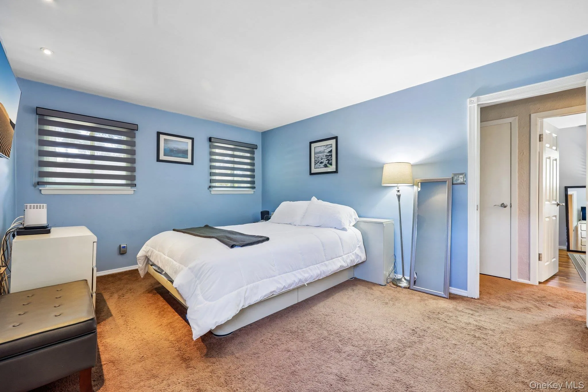 Large Primary Bedroom featuring light blue walls, carpet over wood flooring, two windows with horizontal blinds, and high hat lighting Large Primary Bedroom featuring light blue walls, carpet over wood flooring, two windows with horizontal blinds, and high hat lighting