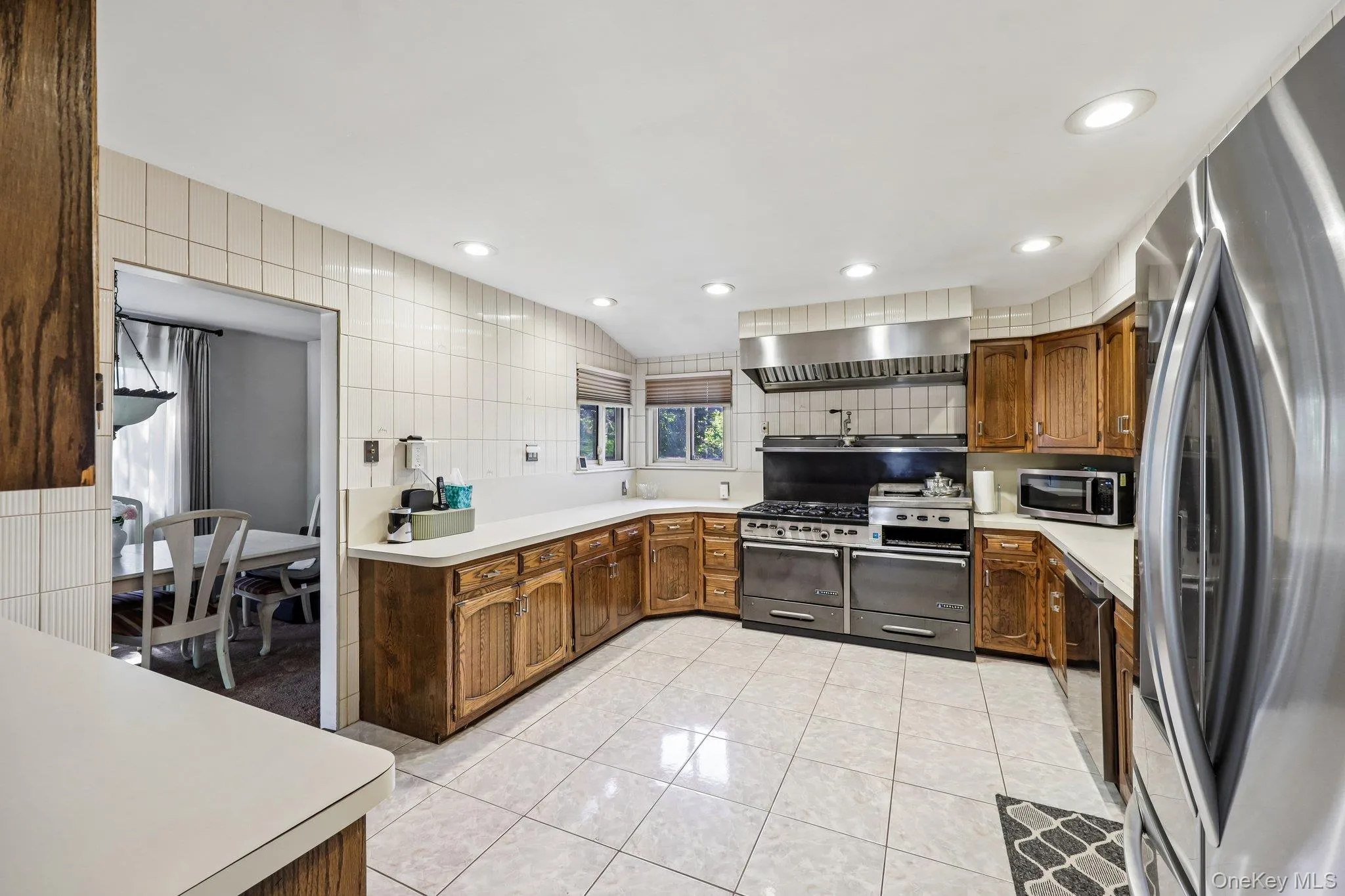 Eat-In-Kitchen featuring wood cabinetry, high hats, lots of counter space, window to yard, tile flooring, stainless steel appliances including a large gas range with professional grade hood Eat-In-Kitchen featuring wood cabinetry, high hats, lots of counter space, window to yard, tile flooring, stainless steel appliances including a large gas range with professional grade hood