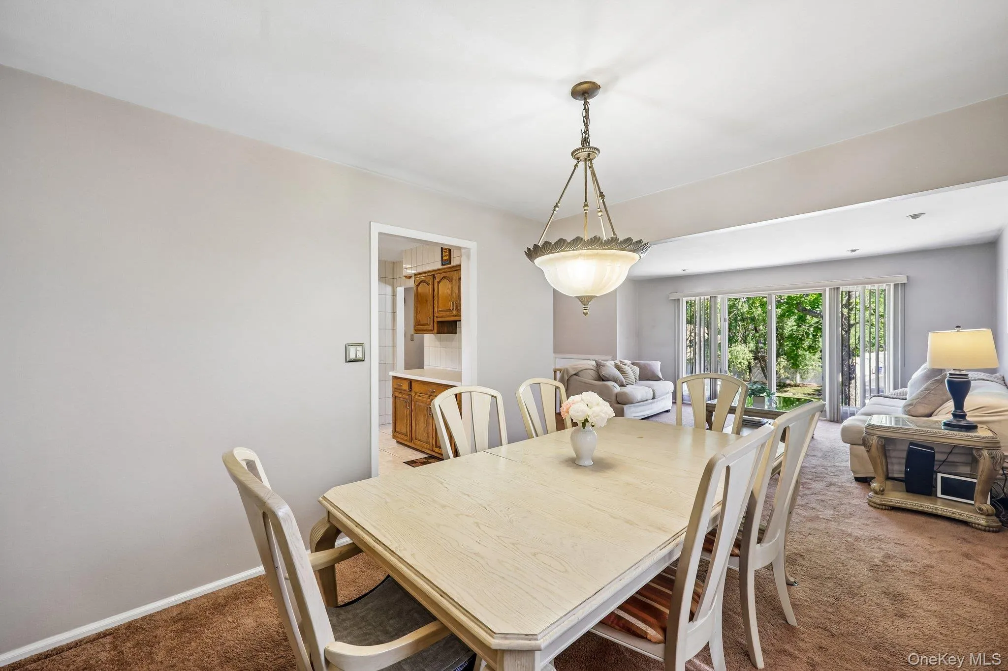 Bright sun filled Dining Room with open concept to Living Room, entrance to Eat-In-Kitchen, carpet over wood floor Bright sun filled Dining Room with open concept to Living Room, entrance to Eat-In-Kitchen, carpet over wood floor