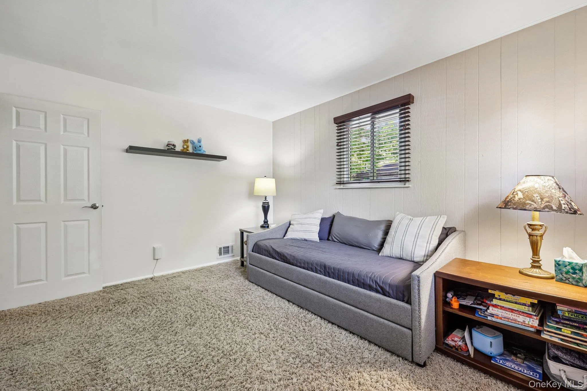 Bright bedroom with white wood paneled wall, carpeting over wood floor, closet, windows bringing in plenty of light. Bright bedroom with white wood paneled wall, carpeting over wood floor, closet, windows bringing in plenty of light.