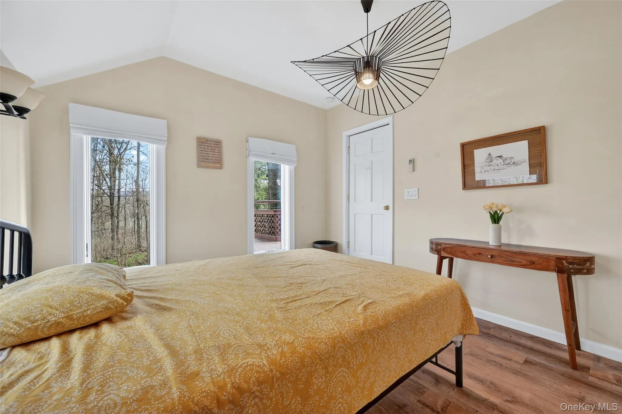 Vaulted ceilings with an architectural light fixture, wood-finish flooring, and two windows offering exterior views Vaulted ceilings with an architectural light fixture, wood-finish flooring, and two windows offering exterior views