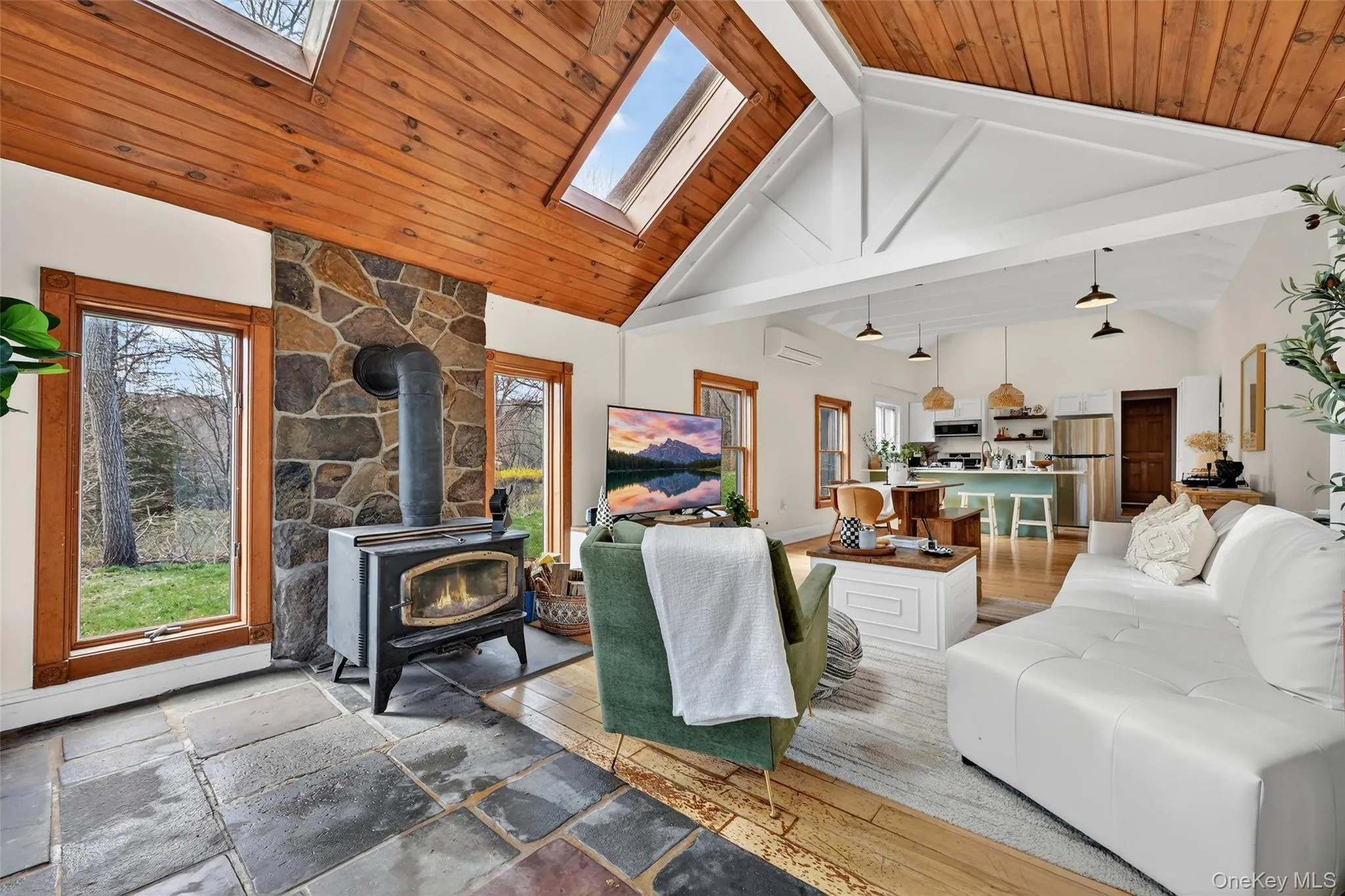 Vaulted wood-paneled ceilings with skylights, stone-faced wood-burning stove, and slate-style flooring Vaulted wood-paneled ceilings with skylights, stone-faced wood-burning stove, and slate-style flooring