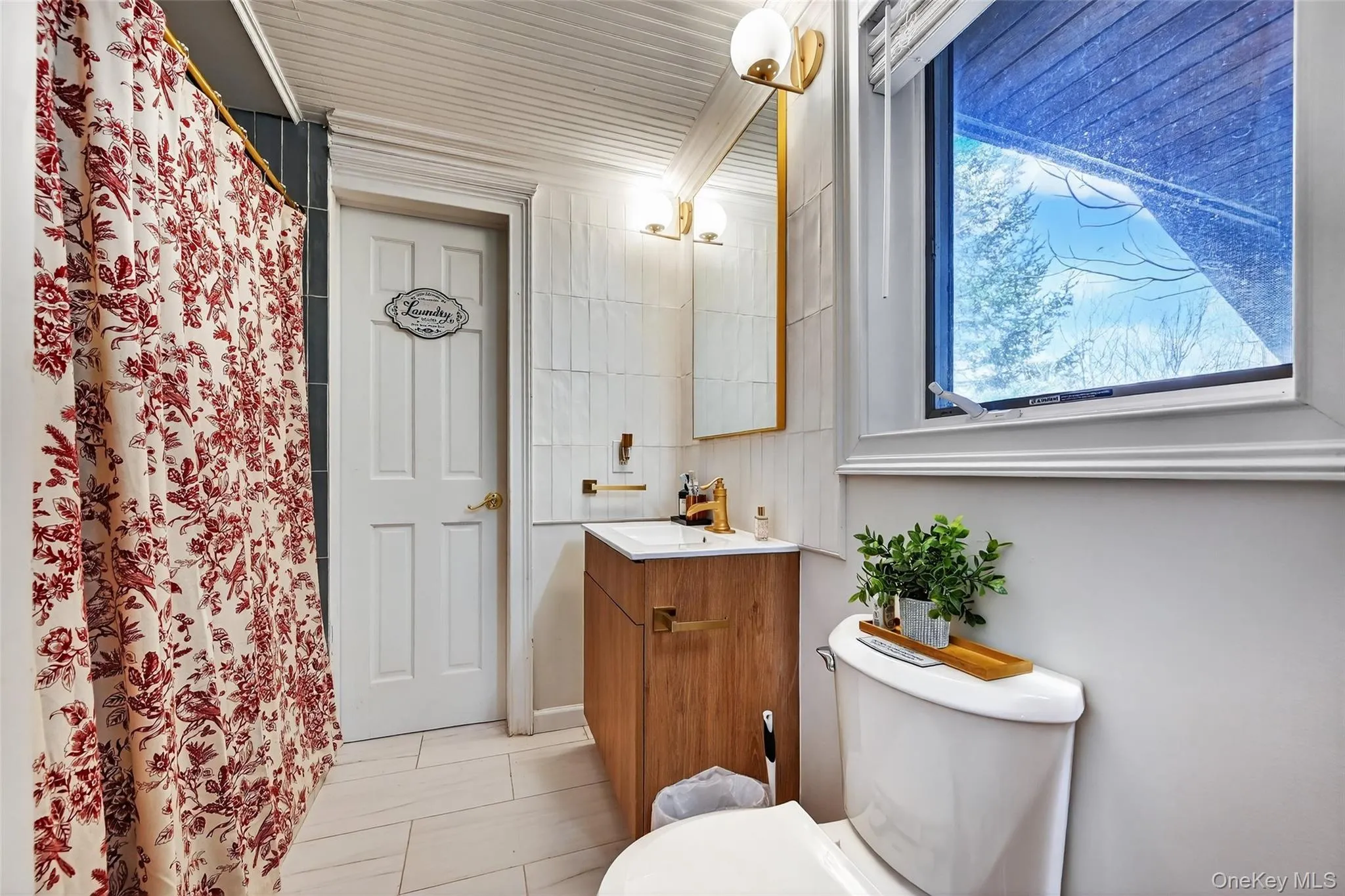 Bathroom featuring a wood-finish vanity with a white countertop and gold-finish fixtures Bathroom featuring a wood-finish vanity with a white countertop and gold-finish fixtures