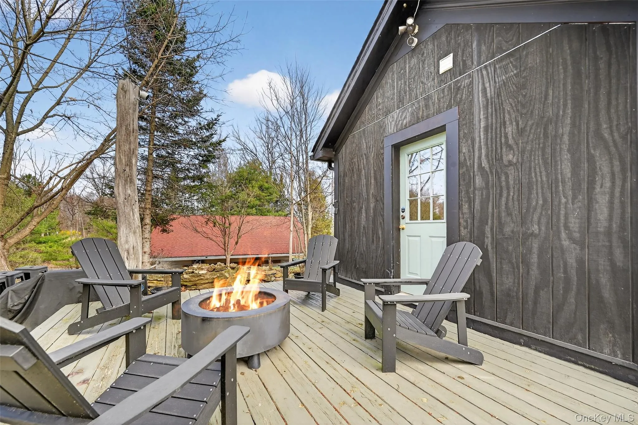 Spacious outdoor deck featuring natural wood planks, a modern fire pit, and ample room for seating Spacious outdoor deck featuring natural wood planks, a modern fire pit, and ample room for seating