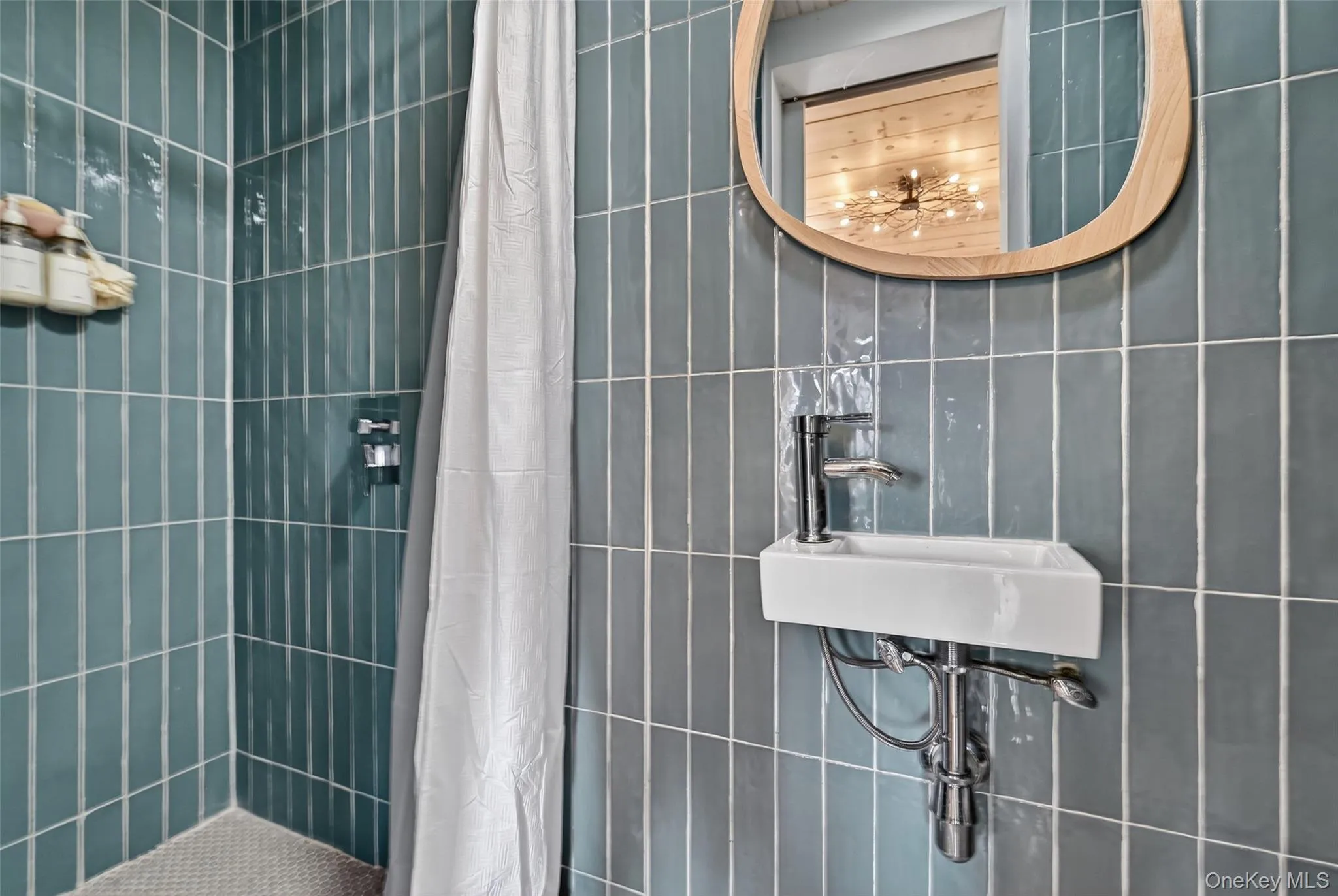Modern bathroom featuring floor-to-ceiling vertical subway tile, a wall-mounted rectangular basin, and a contemporary wood-framed mirror Modern bathroom featuring floor-to-ceiling vertical subway tile, a wall-mounted rectangular basin, and a contemporary wood-framed mirror