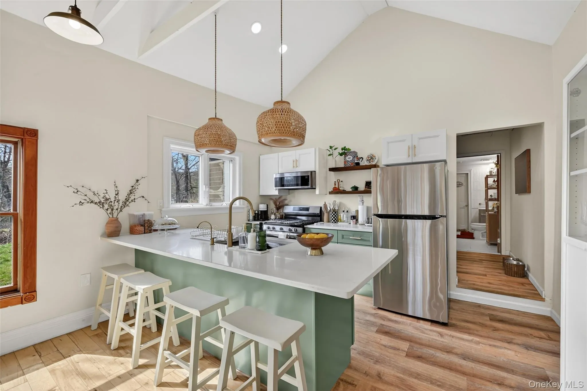 Vaulted ceilings featuring exposed beams over a kitchen with a waterfall island, stainless steel appliances, and a gas range Vaulted ceilings featuring exposed beams over a kitchen with a waterfall island, stainless steel appliances, and a gas range