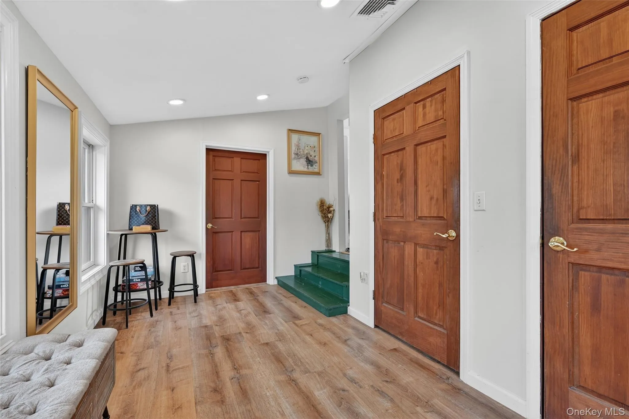 Entryway with wood-finish flooring, light-colored walls, recessed ceiling lighting, and multiple paneled wooden doors Entryway with wood-finish flooring, light-colored walls, recessed ceiling lighting, and multiple paneled wooden doors