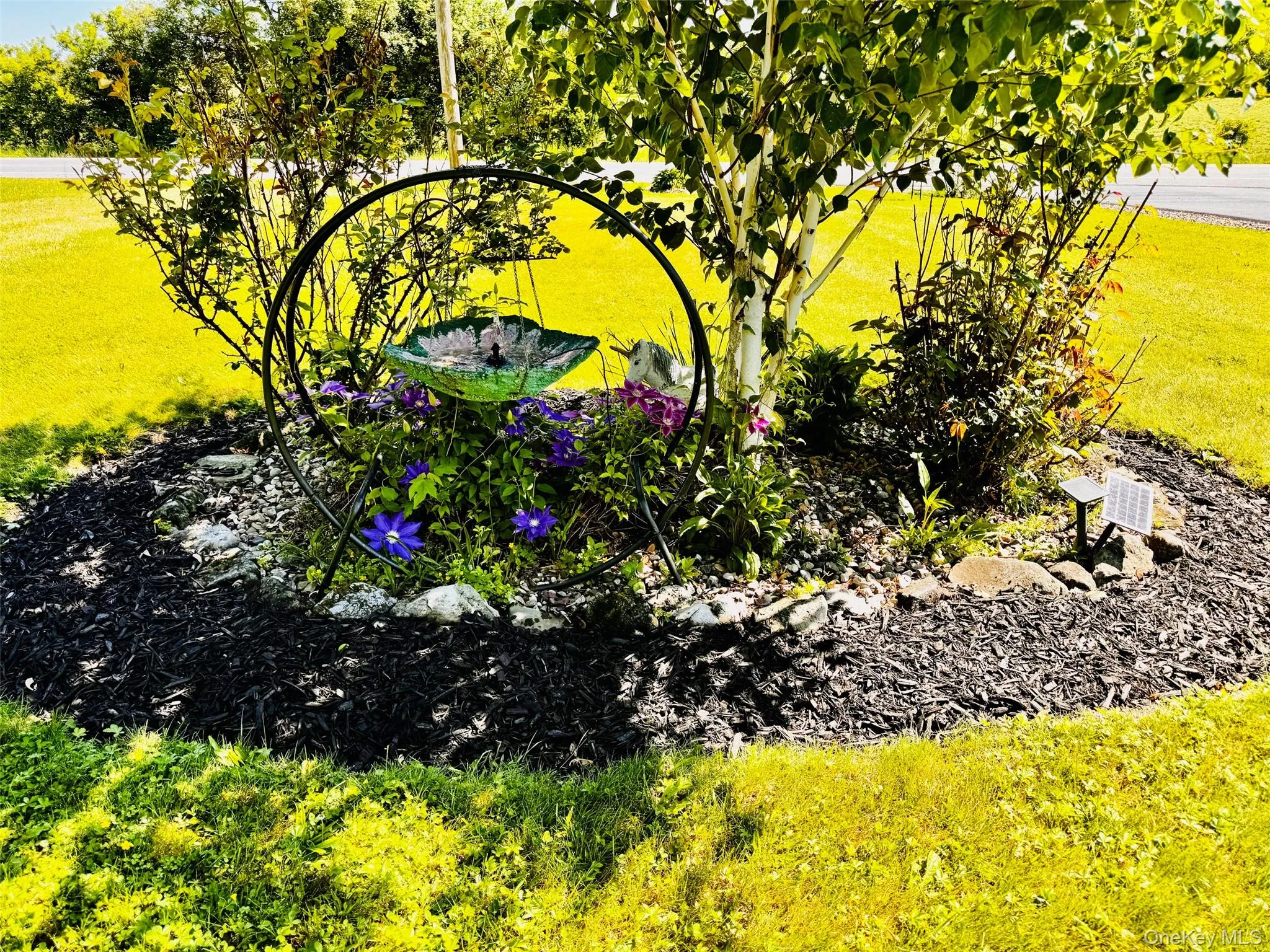 Flower garden with birdbath in front yard. Flower garden with birdbath in front yard.