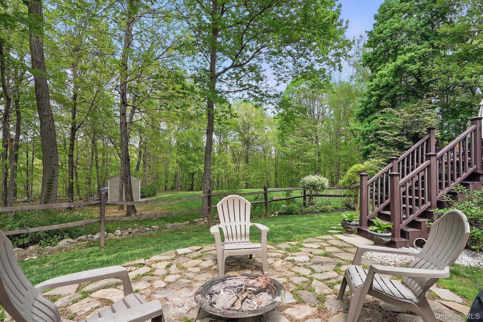 View of patio / terrace featuring a fire pit, fence, and stairs View of patio / terrace featuring a fire pit, fence, and stairs