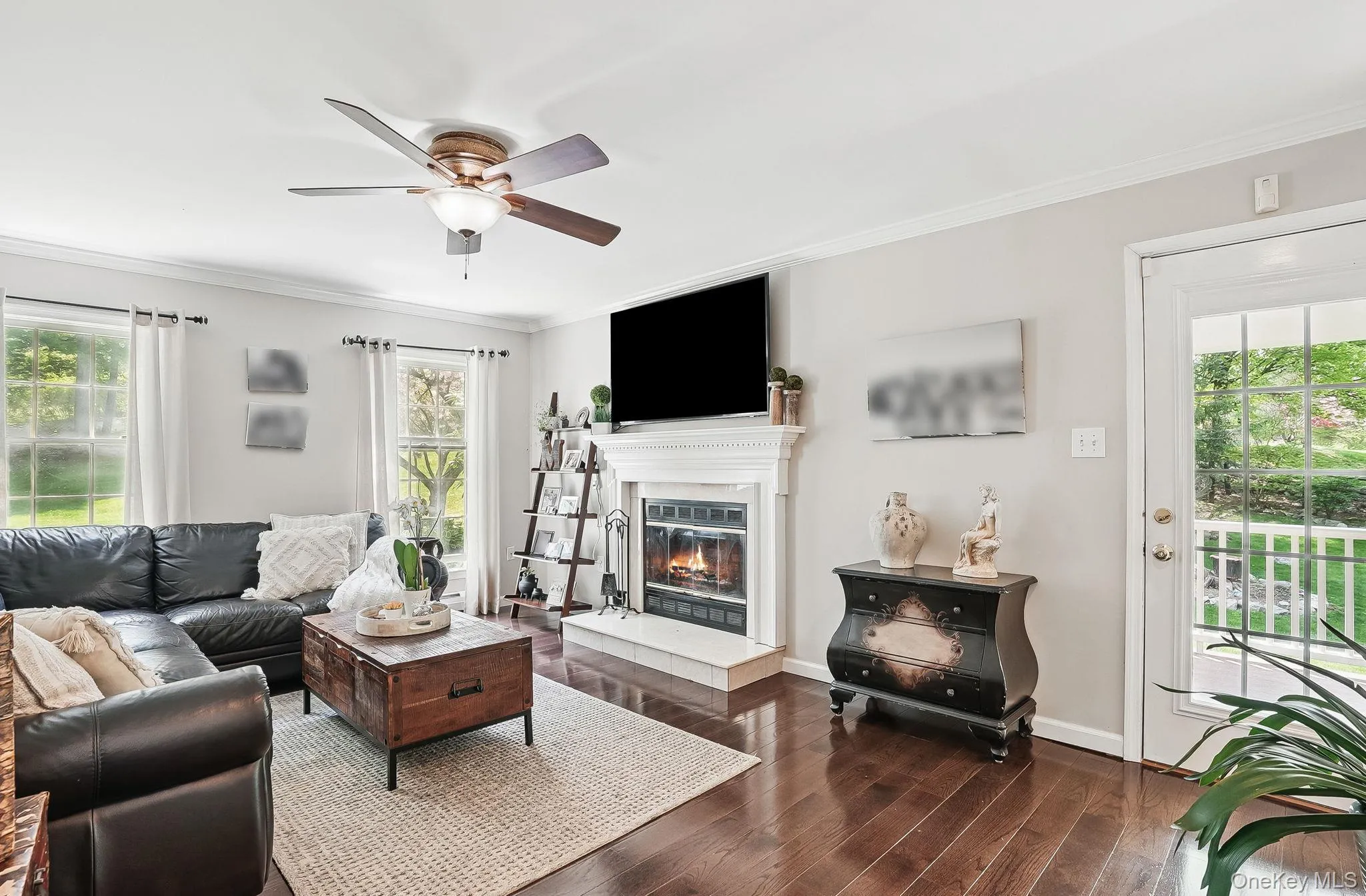 Living area with ornamental molding, a ceiling fan, wood finished floors, a glass covered fireplace, and baseboards Living area with ornamental molding, a ceiling fan, wood finished floors, a glass covered fireplace, and baseboards