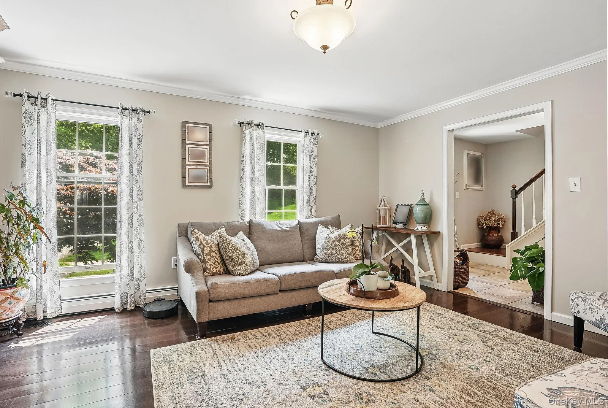 Living room with plenty of natural light, crown molding, hardwood / wood-style flooring, and stairs Living room with plenty of natural light, crown molding, hardwood / wood-style flooring, and stairs