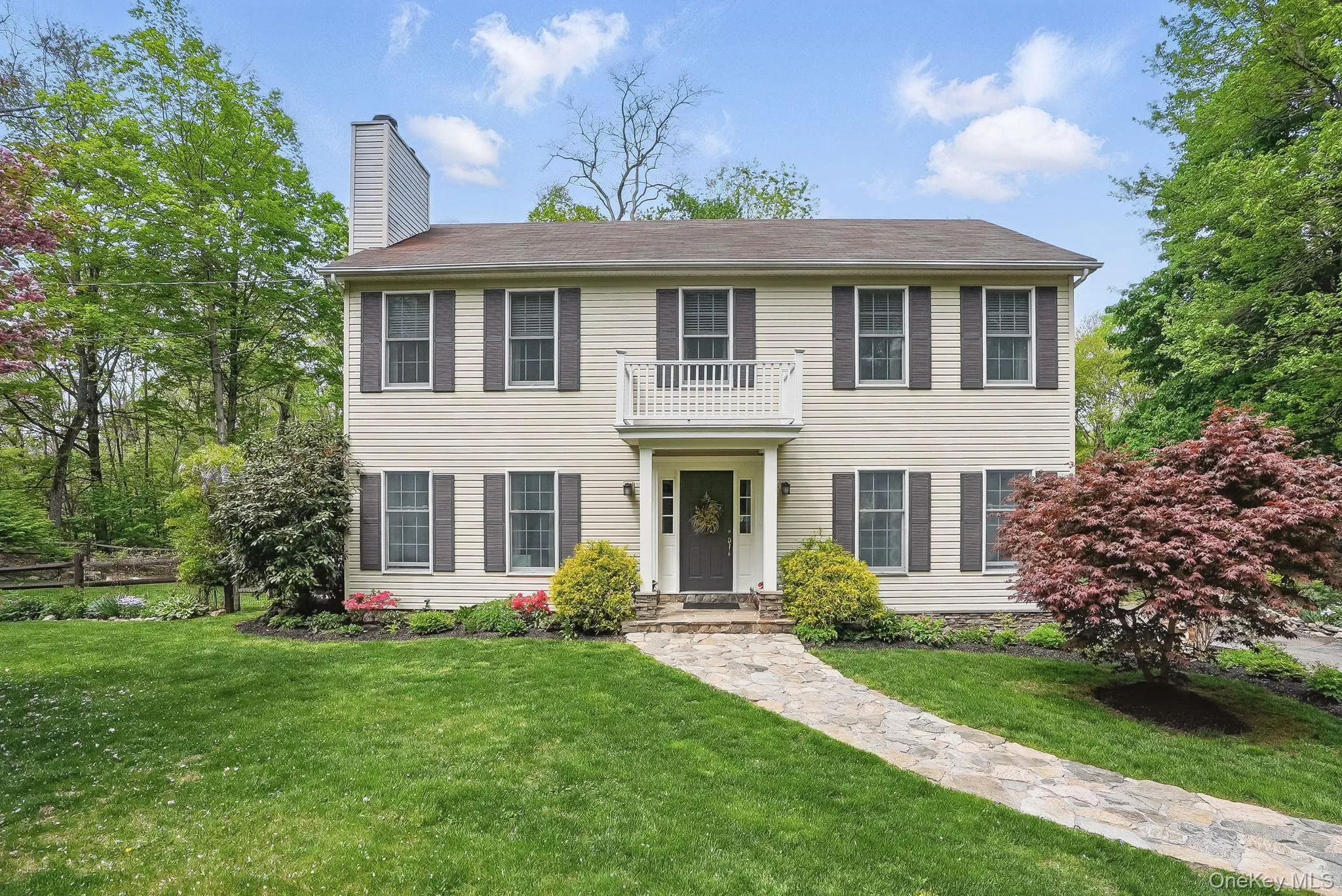 View of front of house featuring a chimney, a balcony, and a front lawn View of front of house featuring a chimney, a balcony, and a front lawn