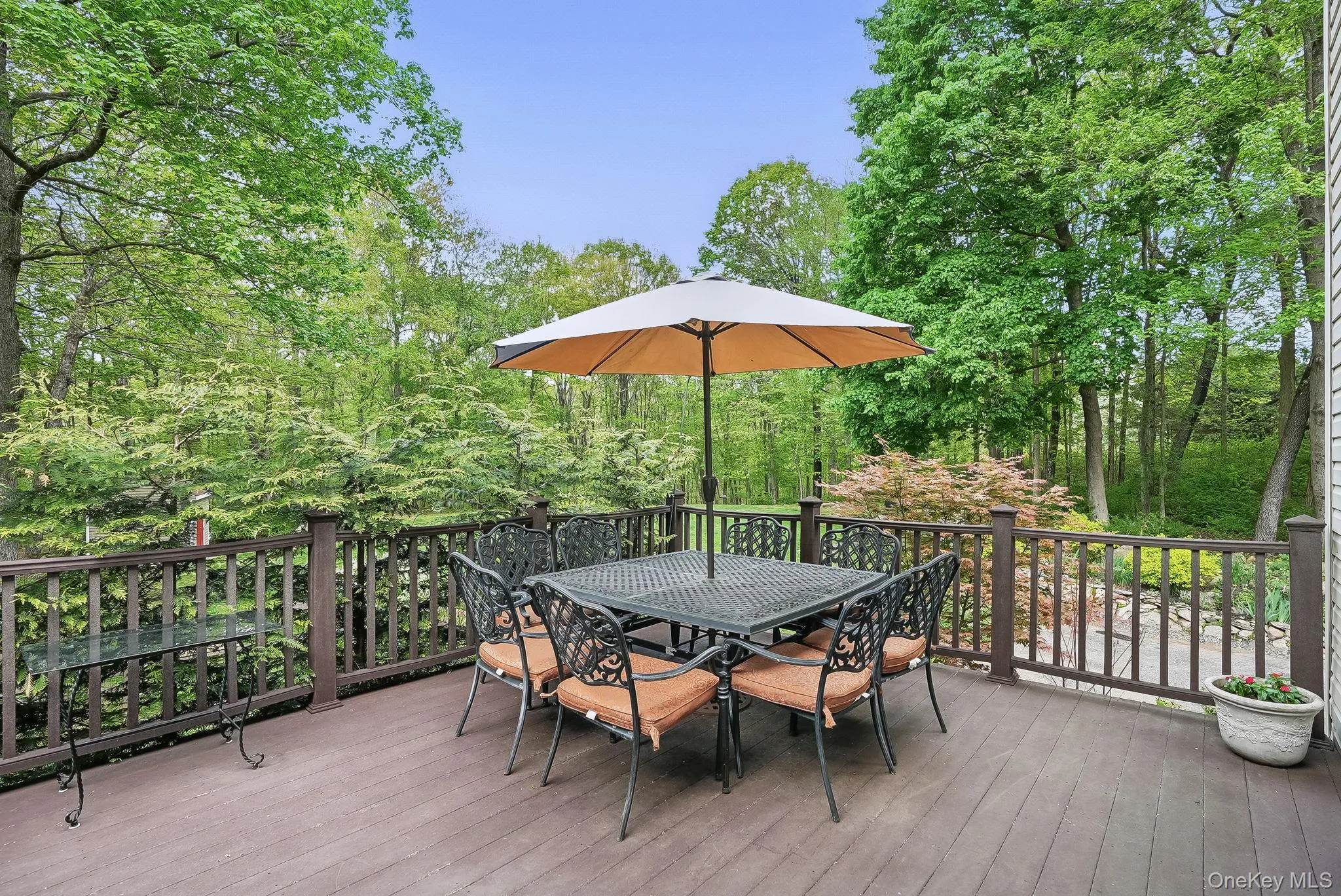 Wooden terrace with outdoor dining space and view of wooded area Wooden terrace with outdoor dining space and view of wooded area