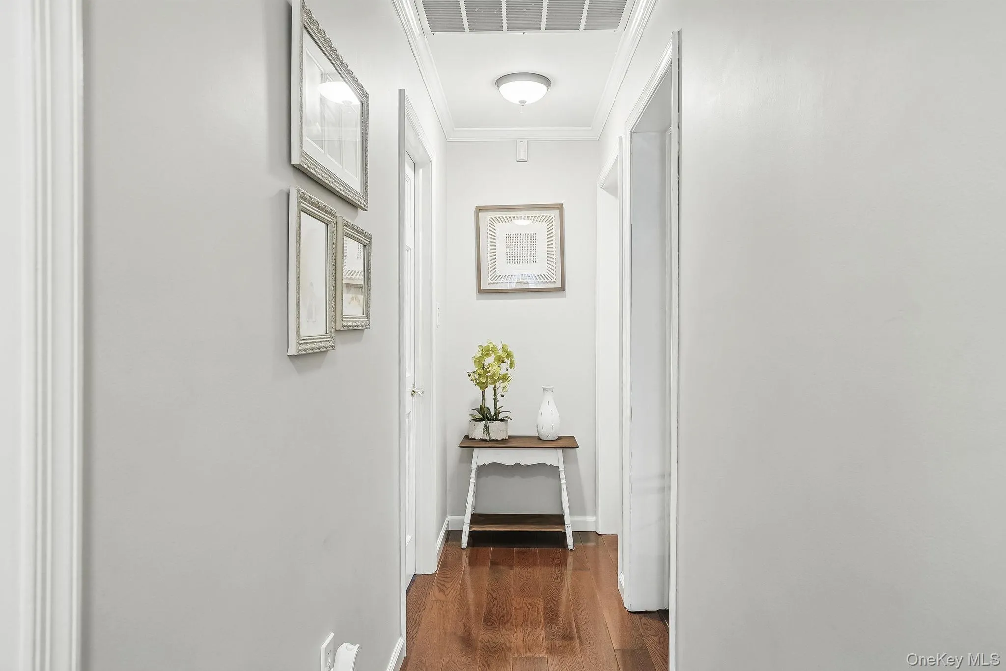 Corridor with dark wood finished floors, ornamental molding, and baseboards Corridor with dark wood finished floors, ornamental molding, and baseboards