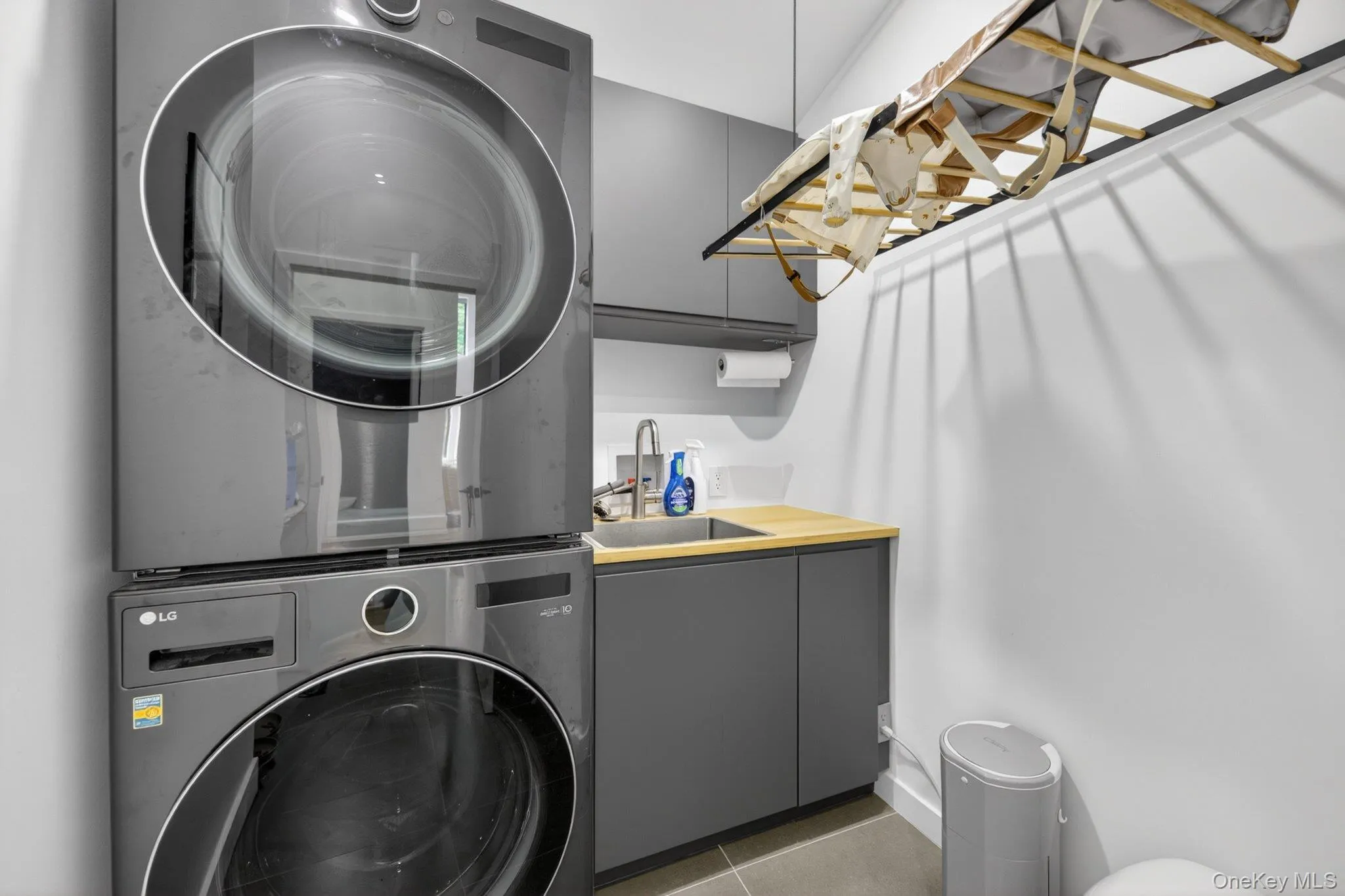 Laundry area featuring stacked appliances and a utility sink Laundry area featuring stacked appliances and a utility sink