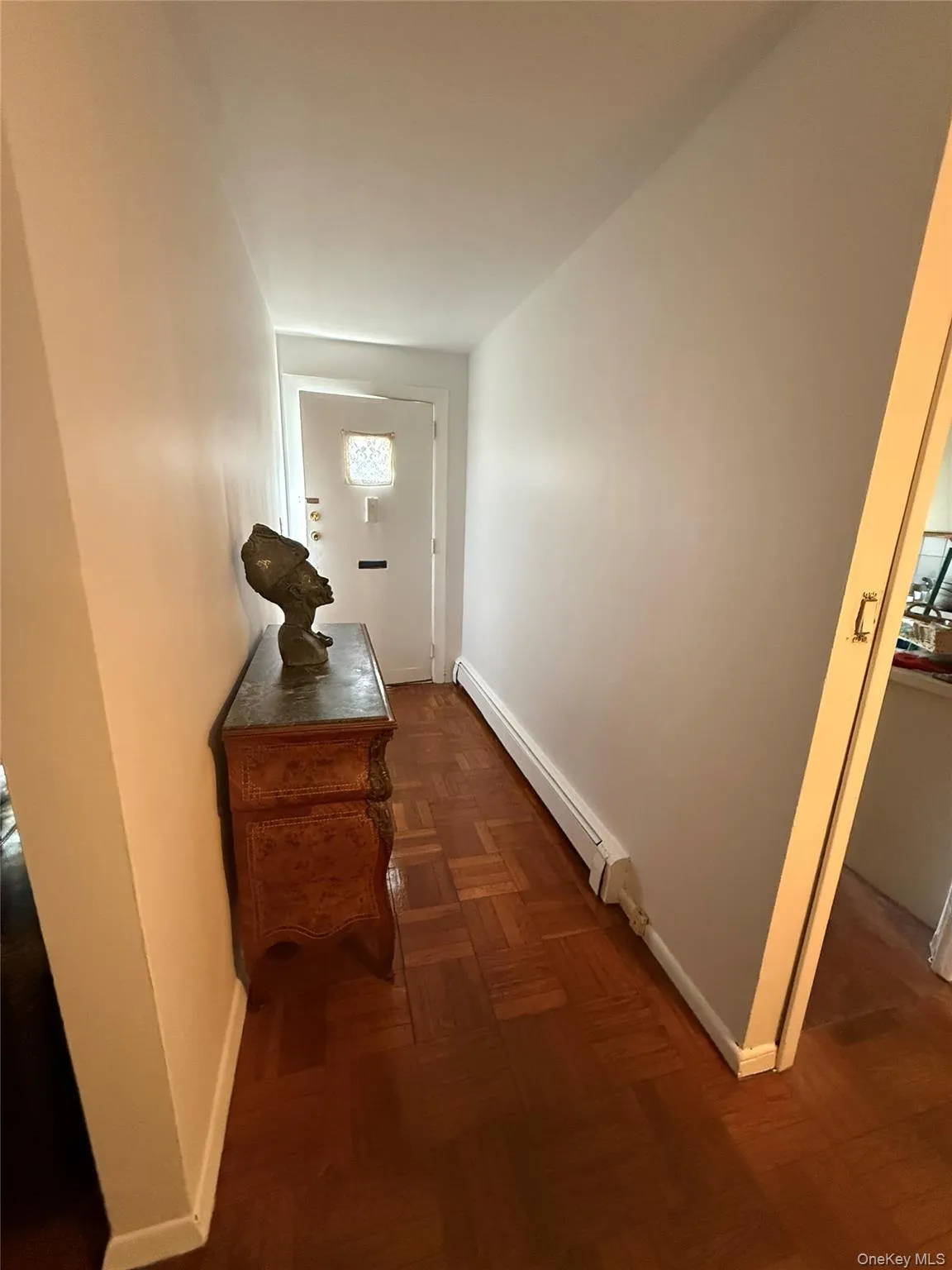 Entryway featuring parquet wood-finish flooring, white walls, and a prominent front door with a decorative glass insert Entryway featuring parquet wood-finish flooring, white walls, and a prominent front door with a decorative glass insert