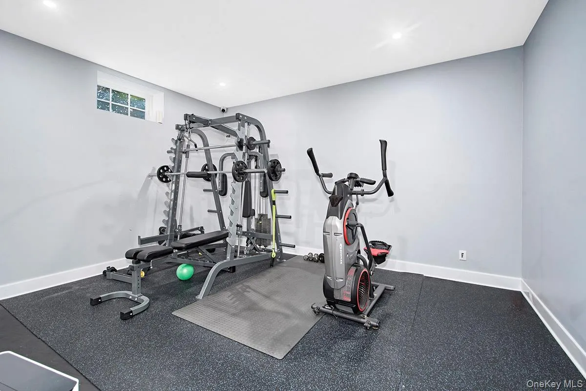 Dedicated exercise room featuring dark speckled flooring, light gray walls, white baseboards, and recessed lighting Dedicated exercise room featuring dark speckled flooring, light gray walls, white baseboards, and recessed lighting