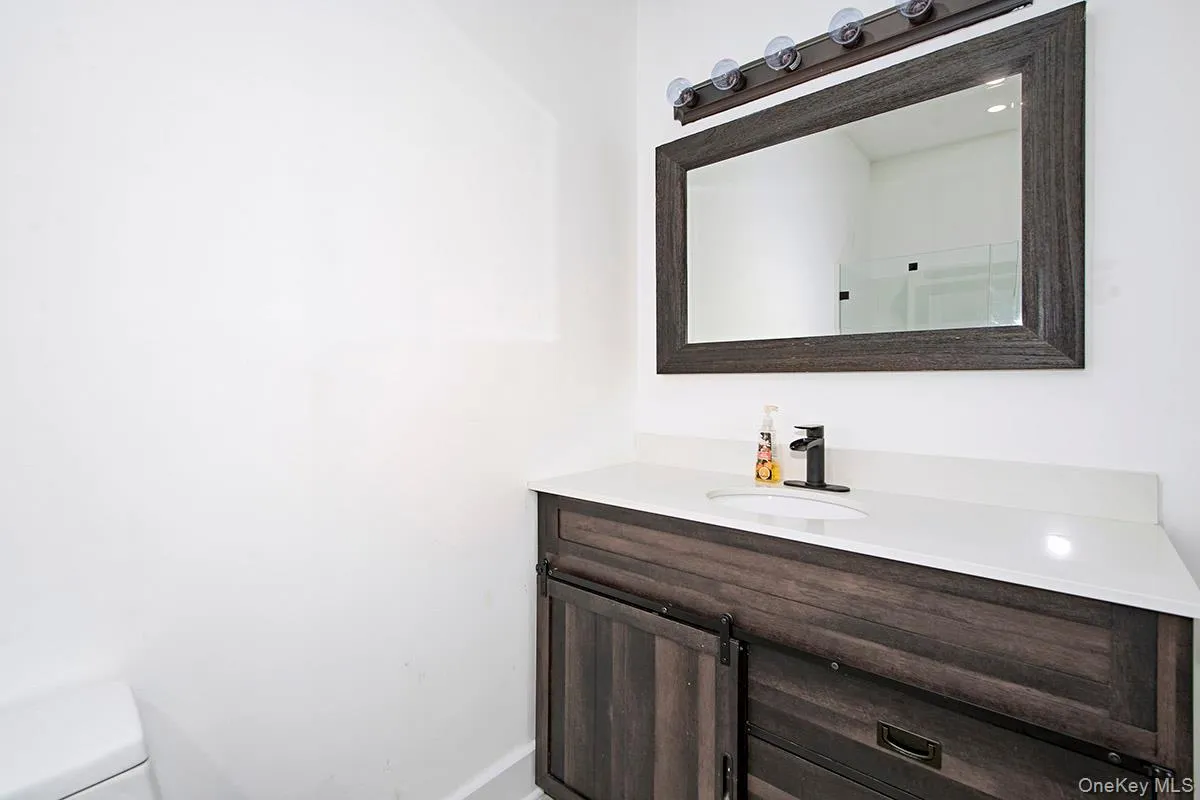 White vanity with a wood-grain finish and barn door style cabinetry White vanity with a wood-grain finish and barn door style cabinetry
