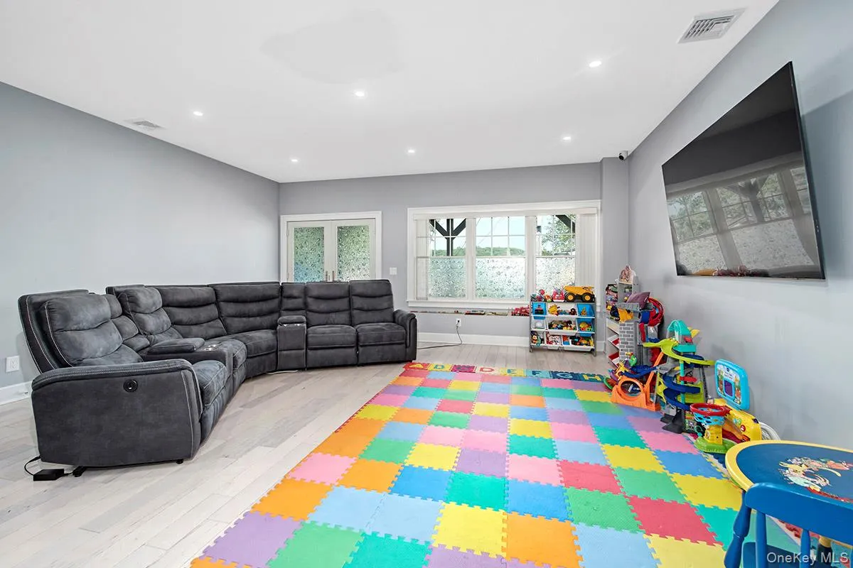 Spacious interior rec room featuring light-colored wood-finish flooring, recessed ceiling lighting, and light grey wall finishes Spacious interior rec room featuring light-colored wood-finish flooring, recessed ceiling lighting, and light grey wall finishes