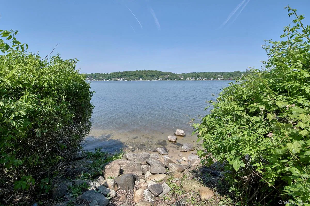 Waterfront access featuring a clear body of water, a rocky shoreline, and mature foliage Waterfront access featuring a clear body of water, a rocky shoreline, and mature foliage