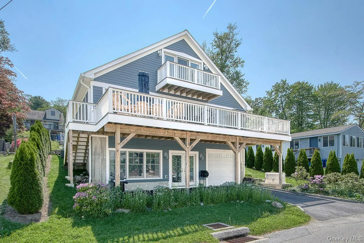 Two-story residence featuring blue siding, white trim, and multiple balconies with white railings Two-story residence featuring blue siding, white trim, and multiple balconies with white railings