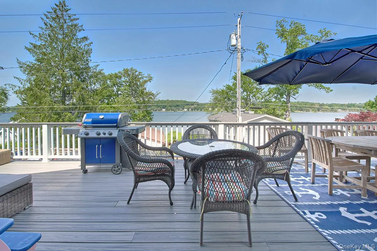 Spacious outdoor deck featuring gray wood-finish flooring and white perimeter railings, with extensive water scenery Spacious outdoor deck featuring gray wood-finish flooring and white perimeter railings, with extensive water scenery