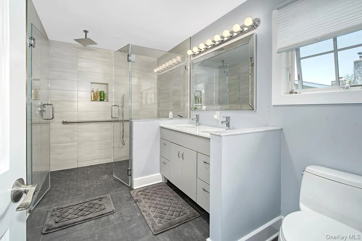 Contemporary bathroom featuring a spacious glass-enclosed shower with a rainfall showerhead, wall niche, and grab bar Contemporary bathroom featuring a spacious glass-enclosed shower with a rainfall showerhead, wall niche, and grab bar