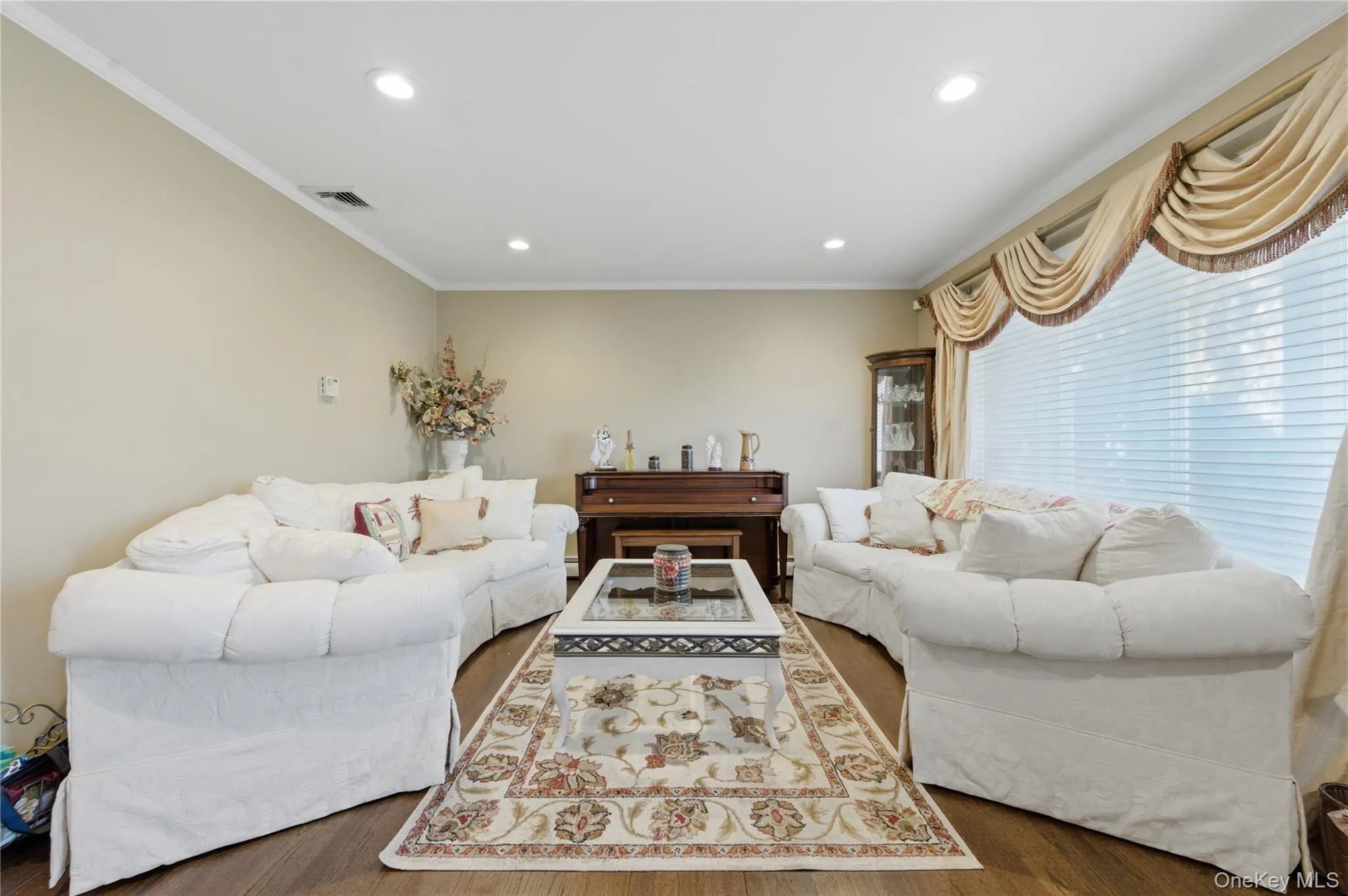 Spacious living area featuring wood-finish flooring, recessed lighting, and crown molding Spacious living area featuring wood-finish flooring, recessed lighting, and crown molding