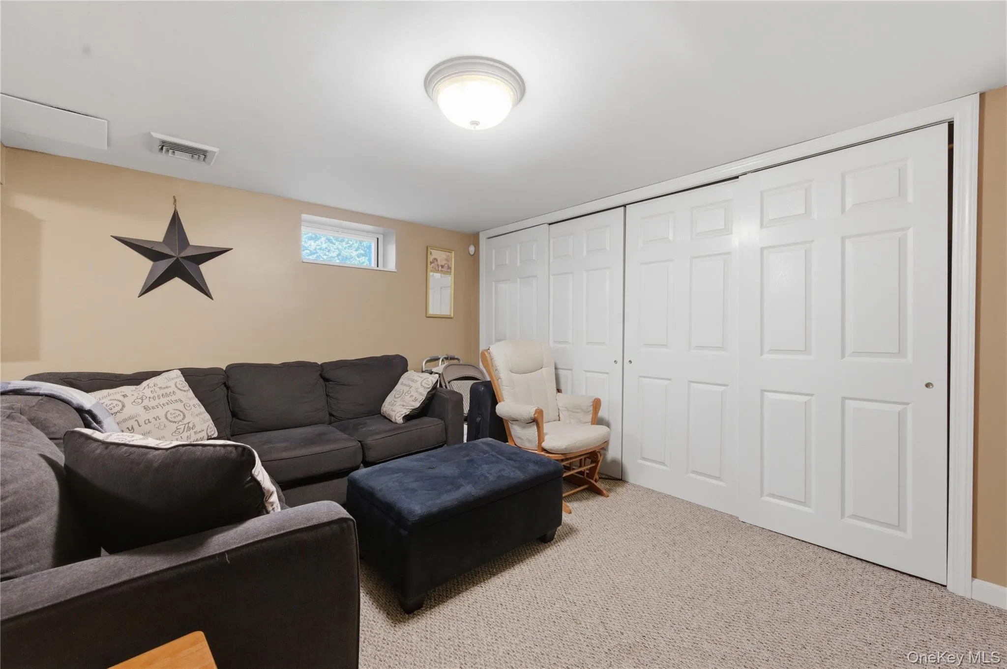 Wall-to-wall carpeting in a neutral tone, featuring white bi-fold closet doors, a transom window, and a ceiling-mounted light fixture Wall-to-wall carpeting in a neutral tone, featuring white bi-fold closet doors, a transom window, and a ceiling-mounted light fixture