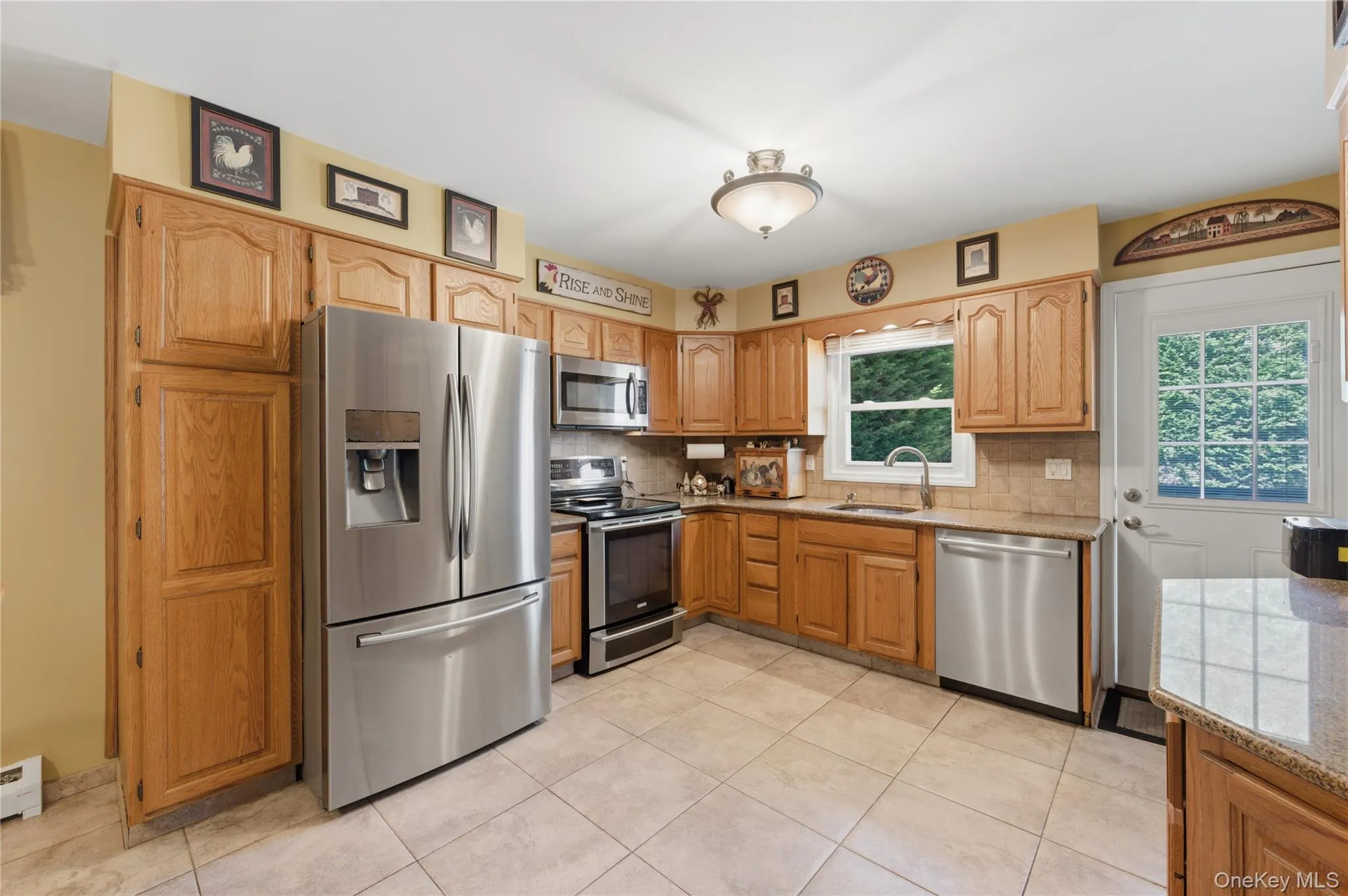 Kitchen featuring light wood cabinetry, stainless steel appliances, and a tiled backsplash Kitchen featuring light wood cabinetry, stainless steel appliances, and a tiled backsplash