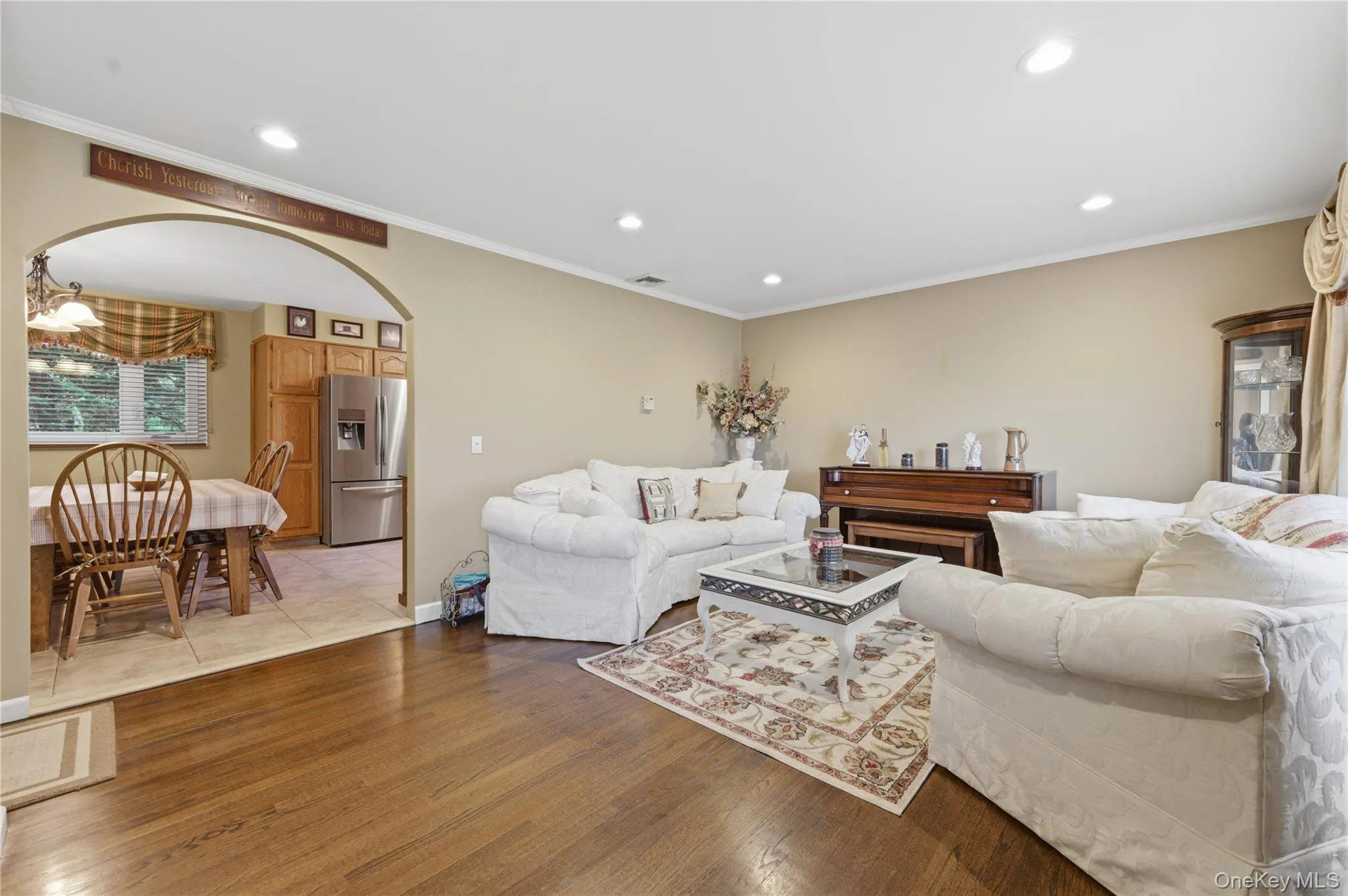 Living room featuring wood-finish flooring, recessed lighting, and an arched entryway to the kitchen Living room featuring wood-finish flooring, recessed lighting, and an arched entryway to the kitchen