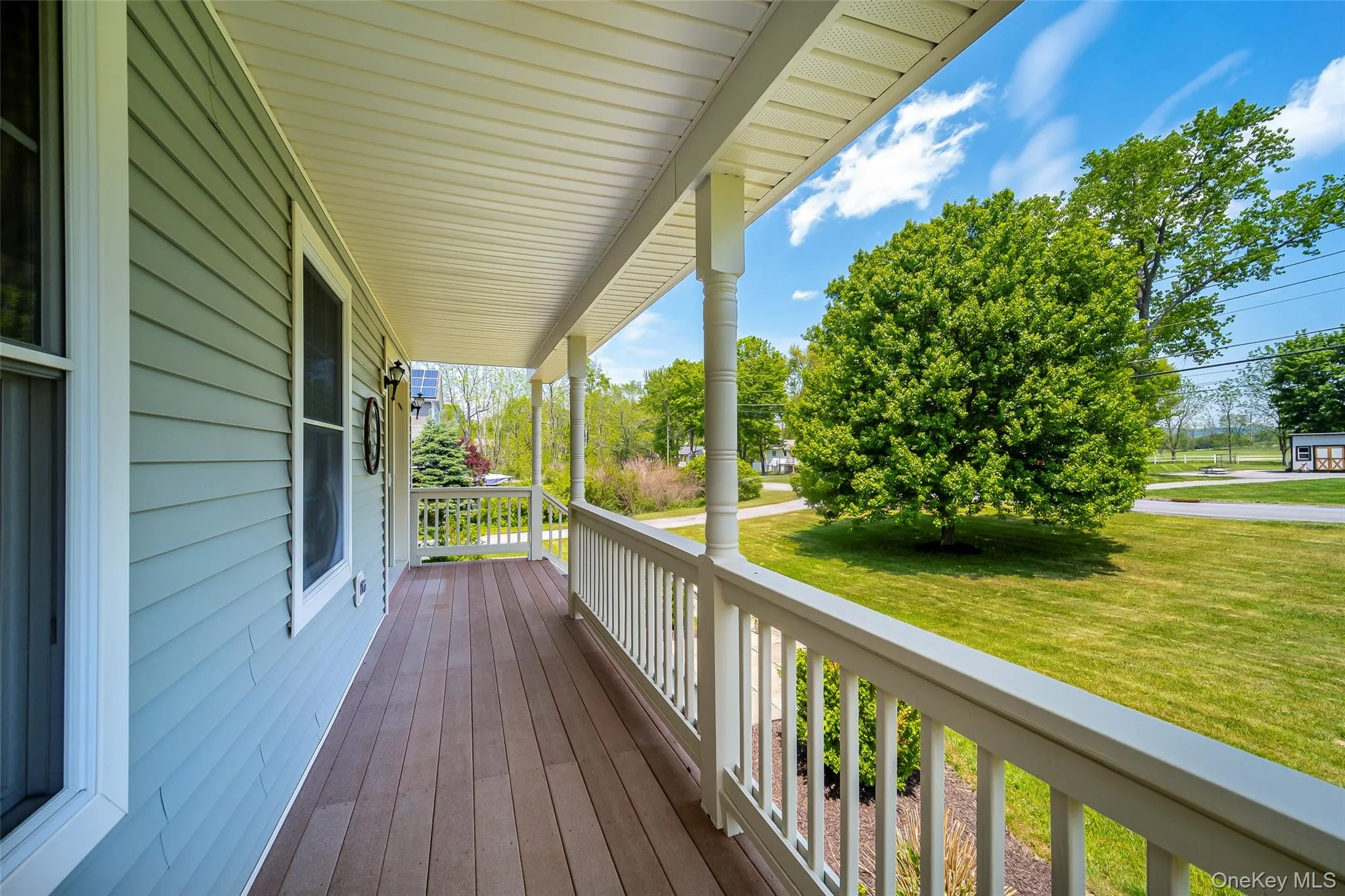 Covered porch featuring wood-finish flooring, white railing, and exterior wall sconces Covered porch featuring wood-finish flooring, white railing, and exterior wall sconces