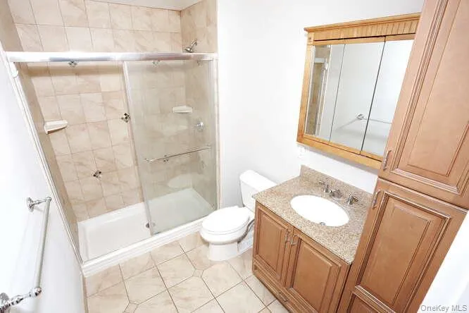 Full bathroom with toilet, a stall shower, vanity, and tile patterned floors Full bathroom with toilet, a stall shower, vanity, and tile patterned floors